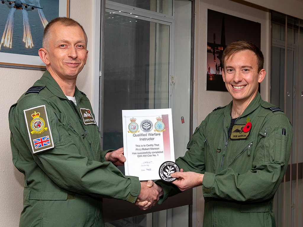 Flight Lieutenant Robert Manson receives his Qualified Warfare Instructor (Air Mobility) course qualification certificate and badge from Commander Air Wing, Group Captain Gareth Burdett.