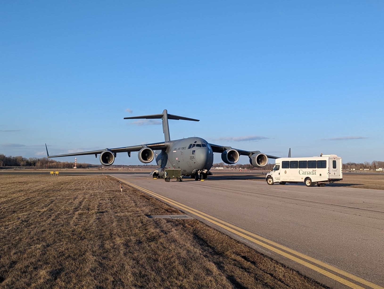 Image shows RAF Globemaster and bus vehicles on the airfield.