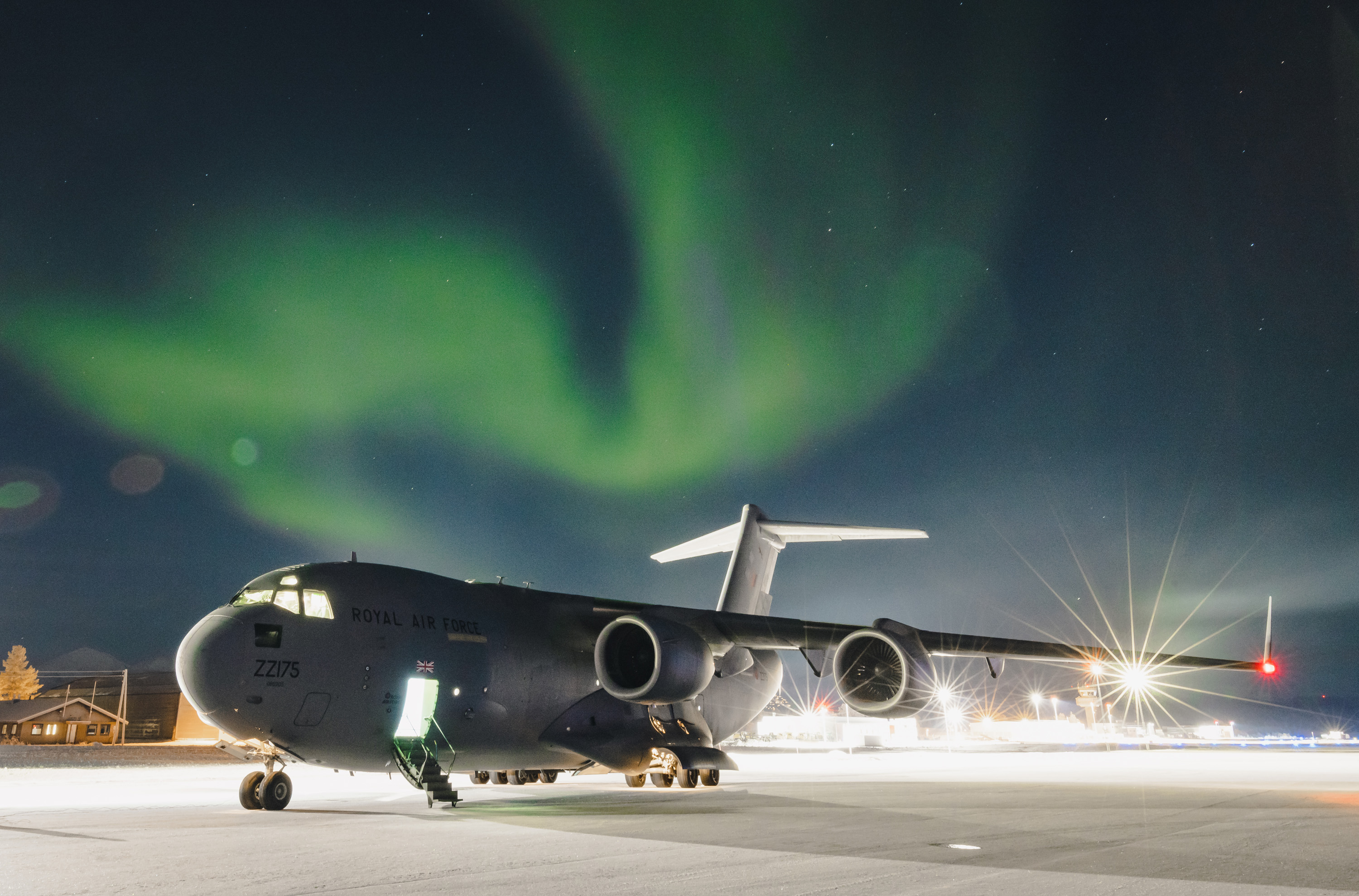Image shows RAF Globemaster on the airfield, below the Northern Lights.