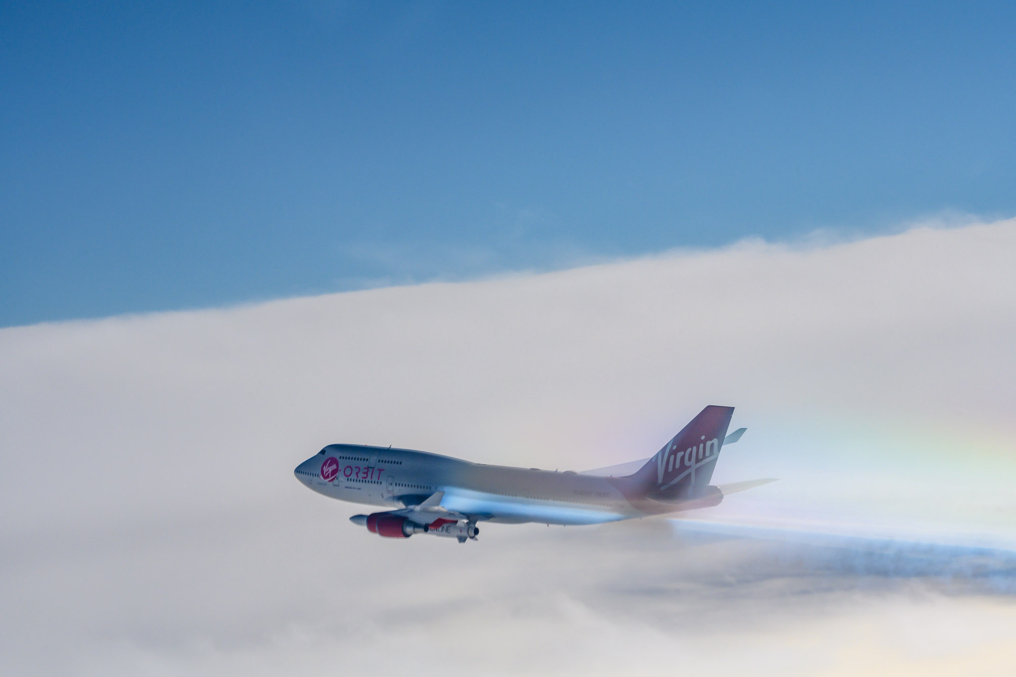 Virgin Orbit Boeing aircraft flying through clouds.