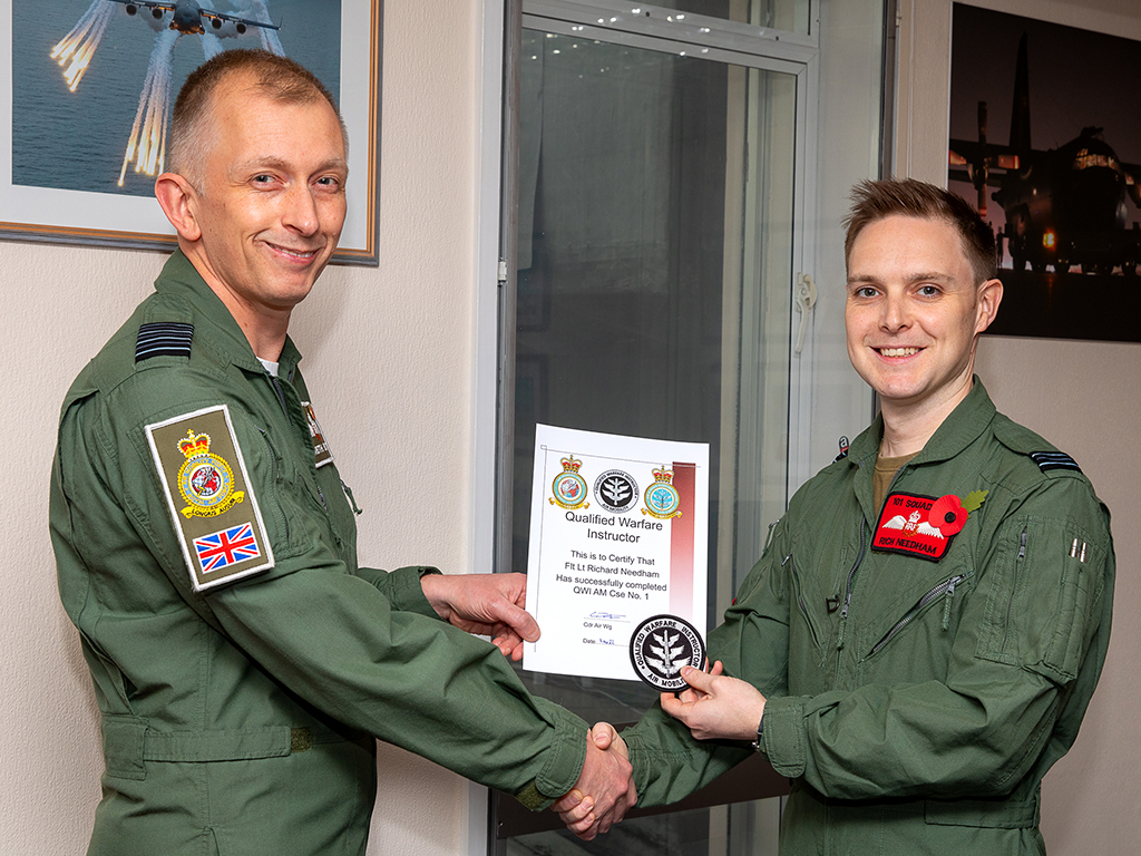 Flight Lieutenant Richard Needham receives his Qualified Warfare Instructor (Air Mobility) course qualification certificate and badge from Commander Air Wing, Group Captain Gareth Burdett.