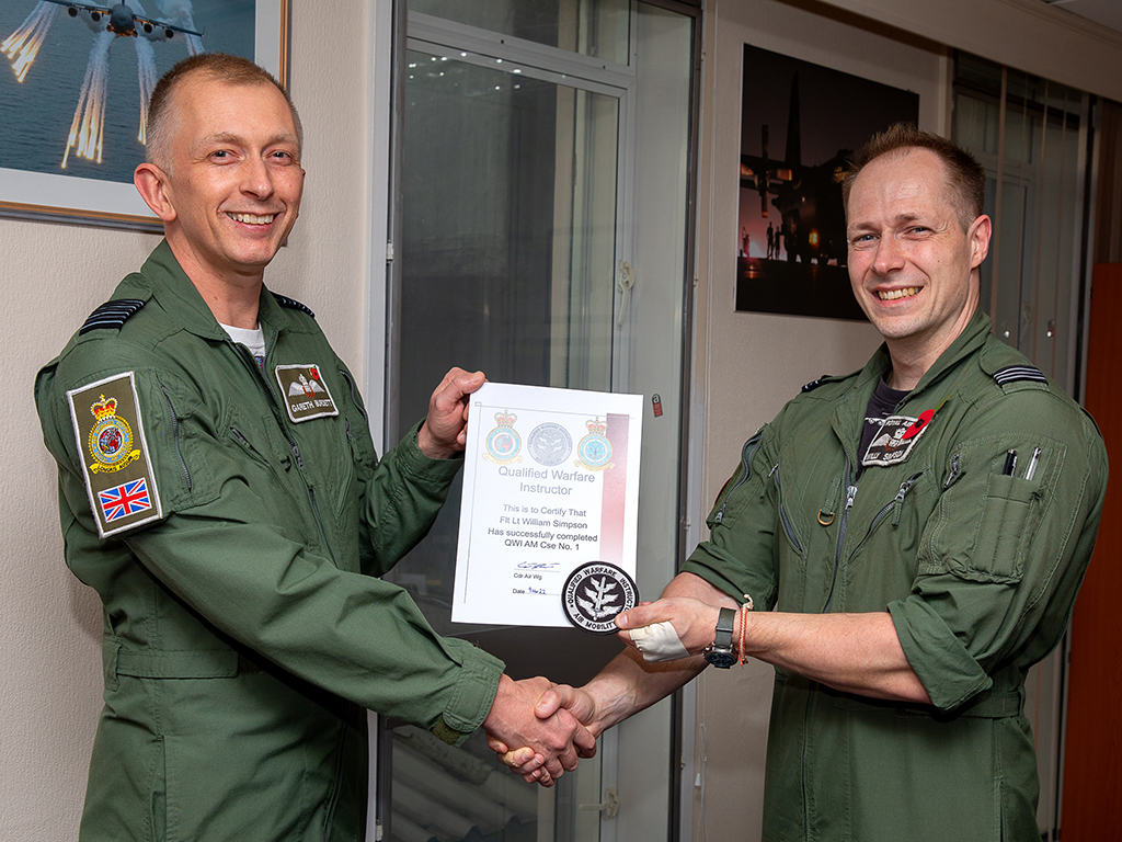 Flight Lieutenant William Simpson receives his Qualified Warfare Instructor (Air Mobility) course qualification certificate and badge from Commander Air Wing, Group Captain Gareth Burdett.