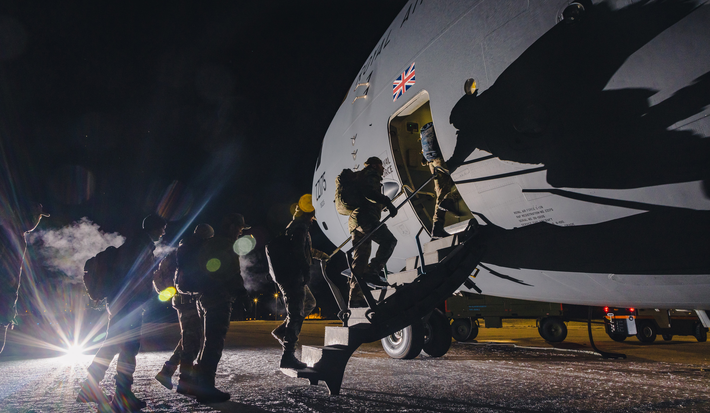 Image shows RAF aviators boarding the Globemaster on the airfield at night.