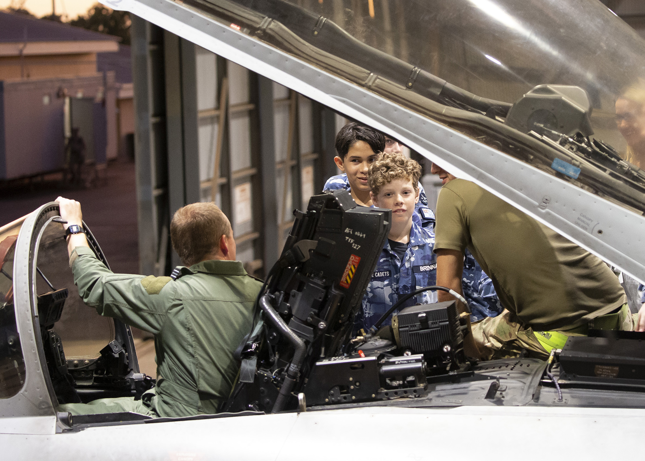 Image shows young Royal Australian Air Force Cadets with RAF aviator in Typhoon cockpit in the hangar.
