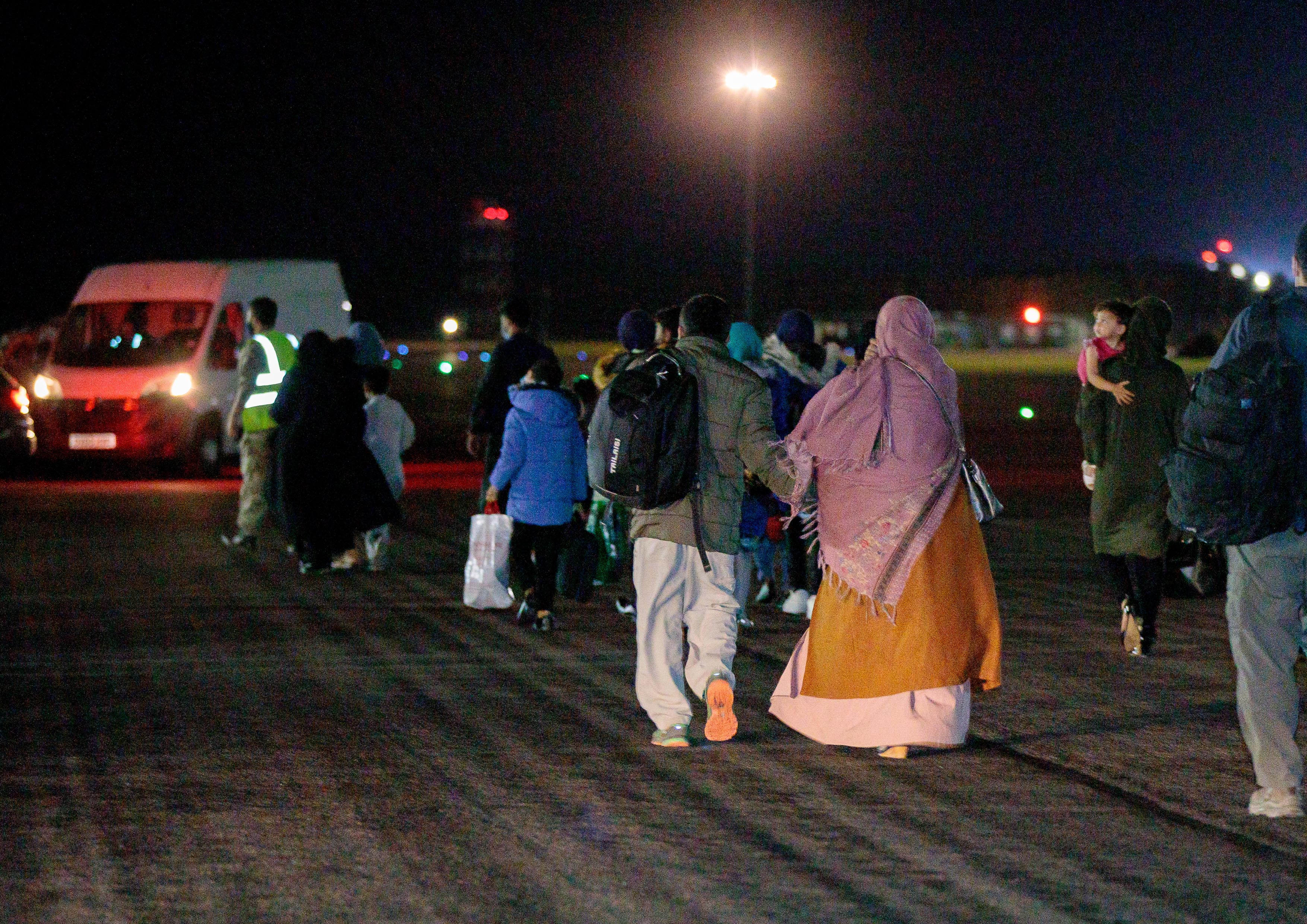 Afghan evacuees evacuate from RAF Brize Norton runway at night. 