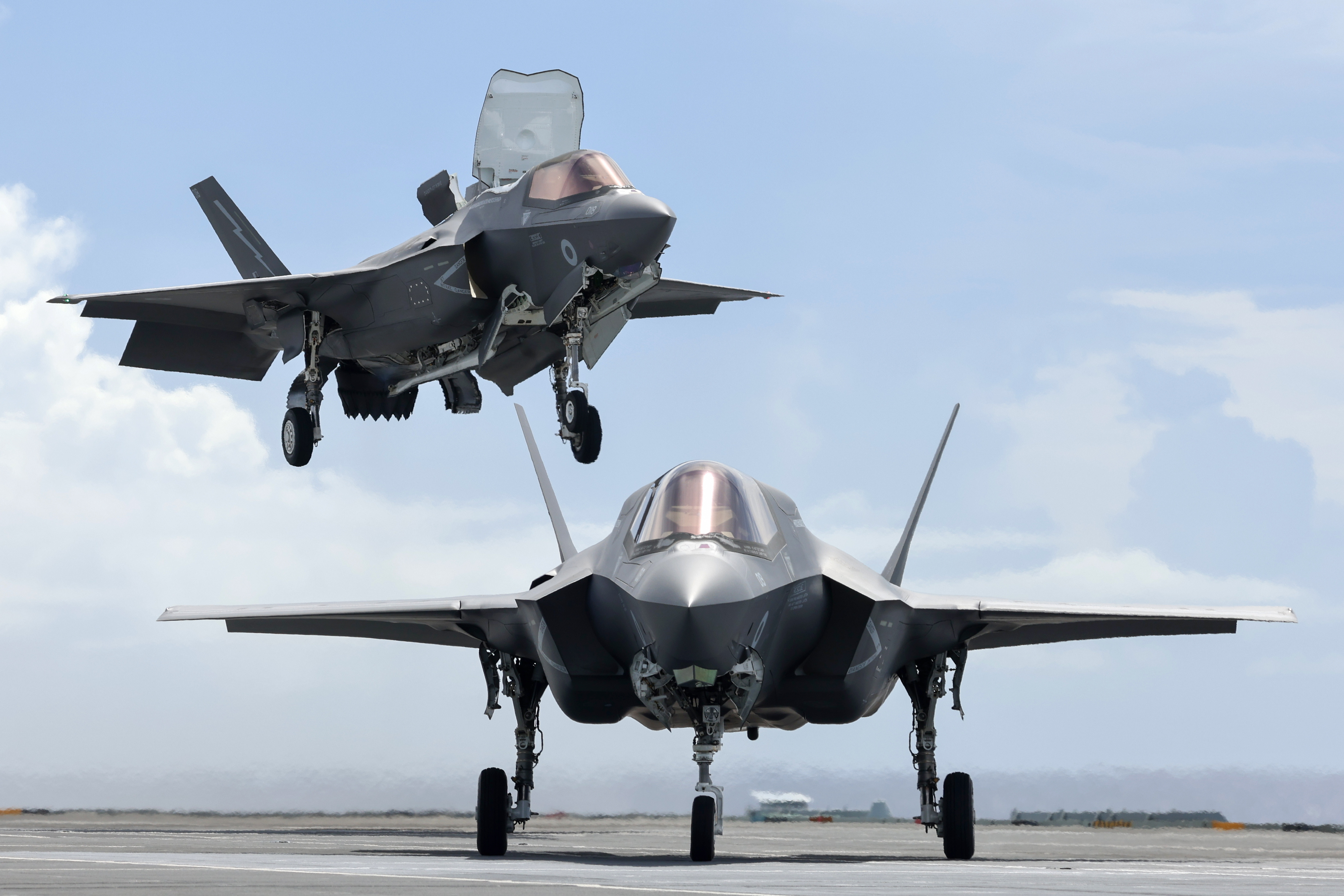 F-35B Lightning taking off, over another on the runway.