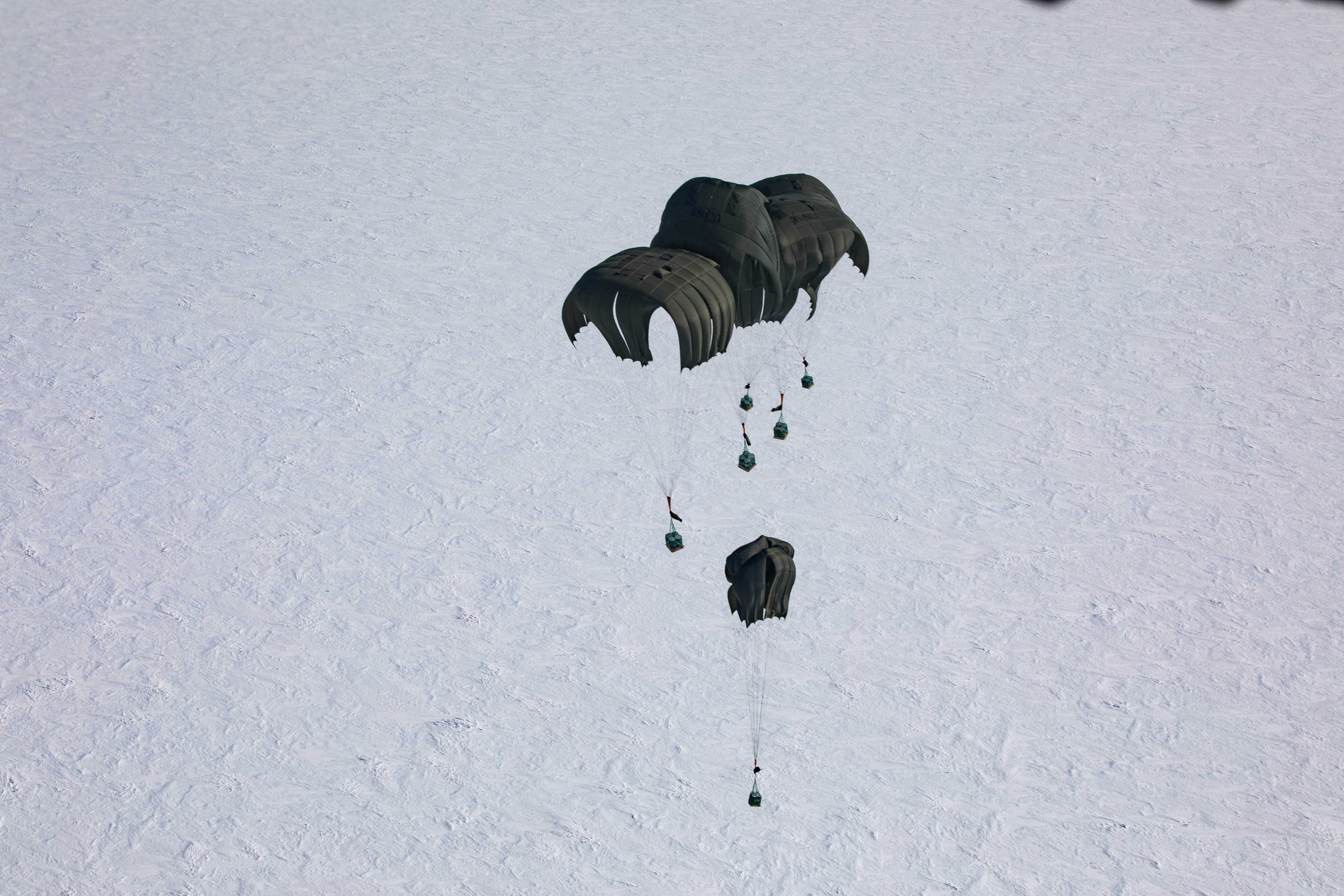 Supplies being parachuted to the ground mid-drop.