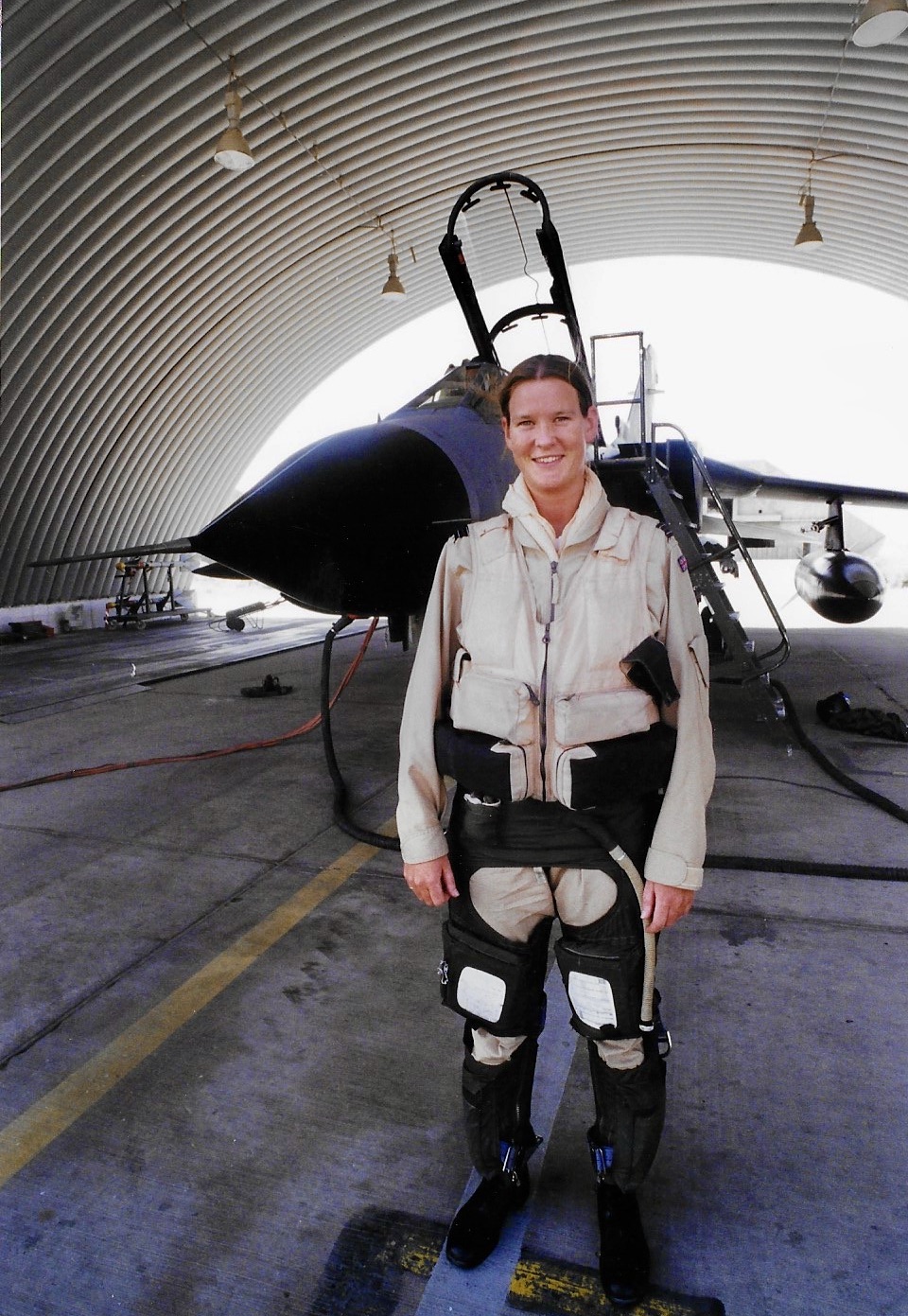 Pilot stands under hangar, before Tornado aircraft.