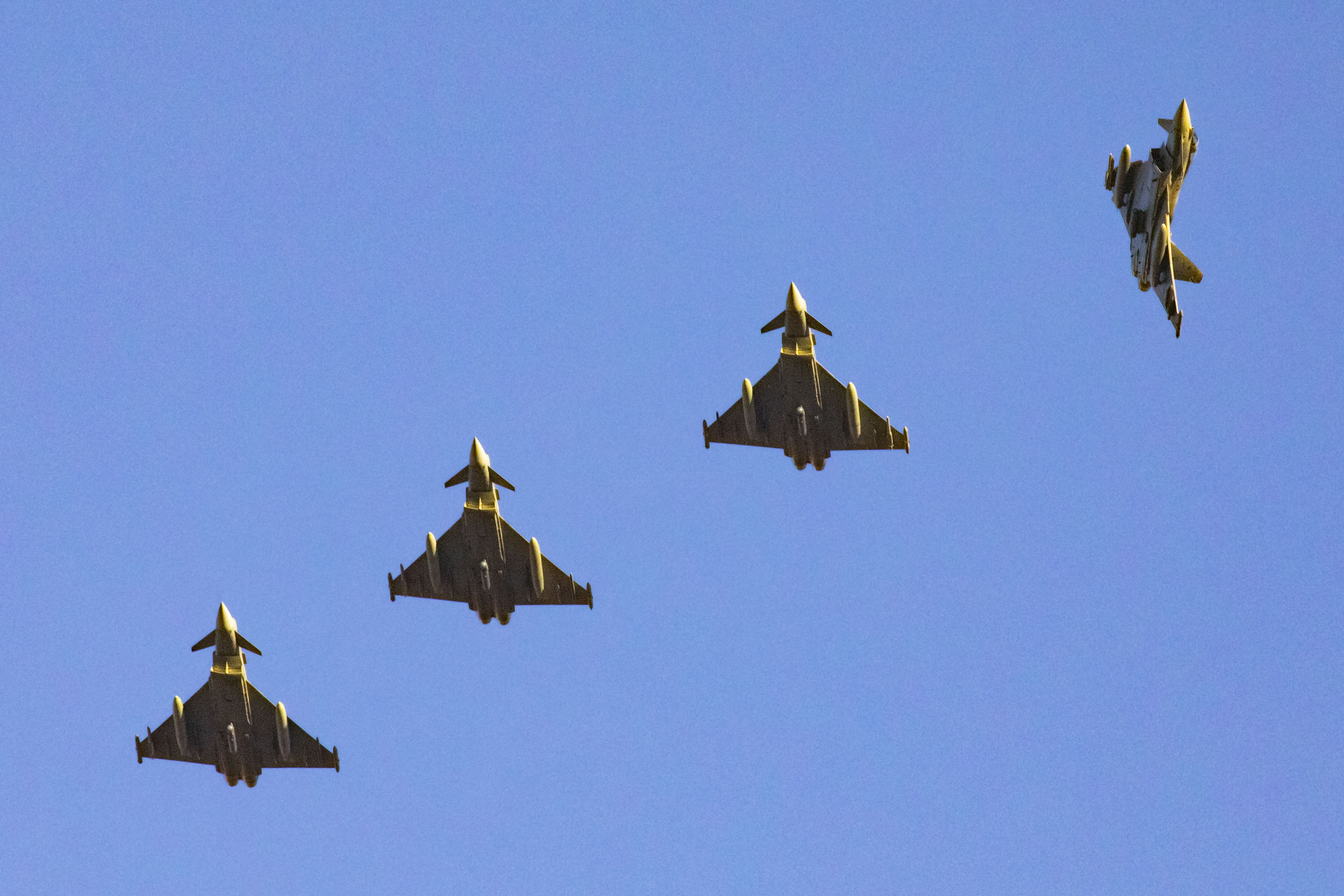 four typhoon aircraft flying in formation, with the right-most typhoon peeling off. bright blue sky