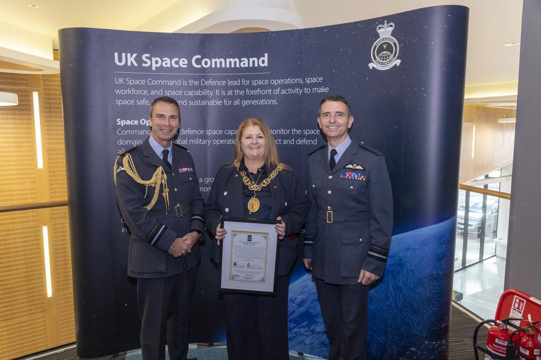 Group photo in front of UK Space Command banner. 