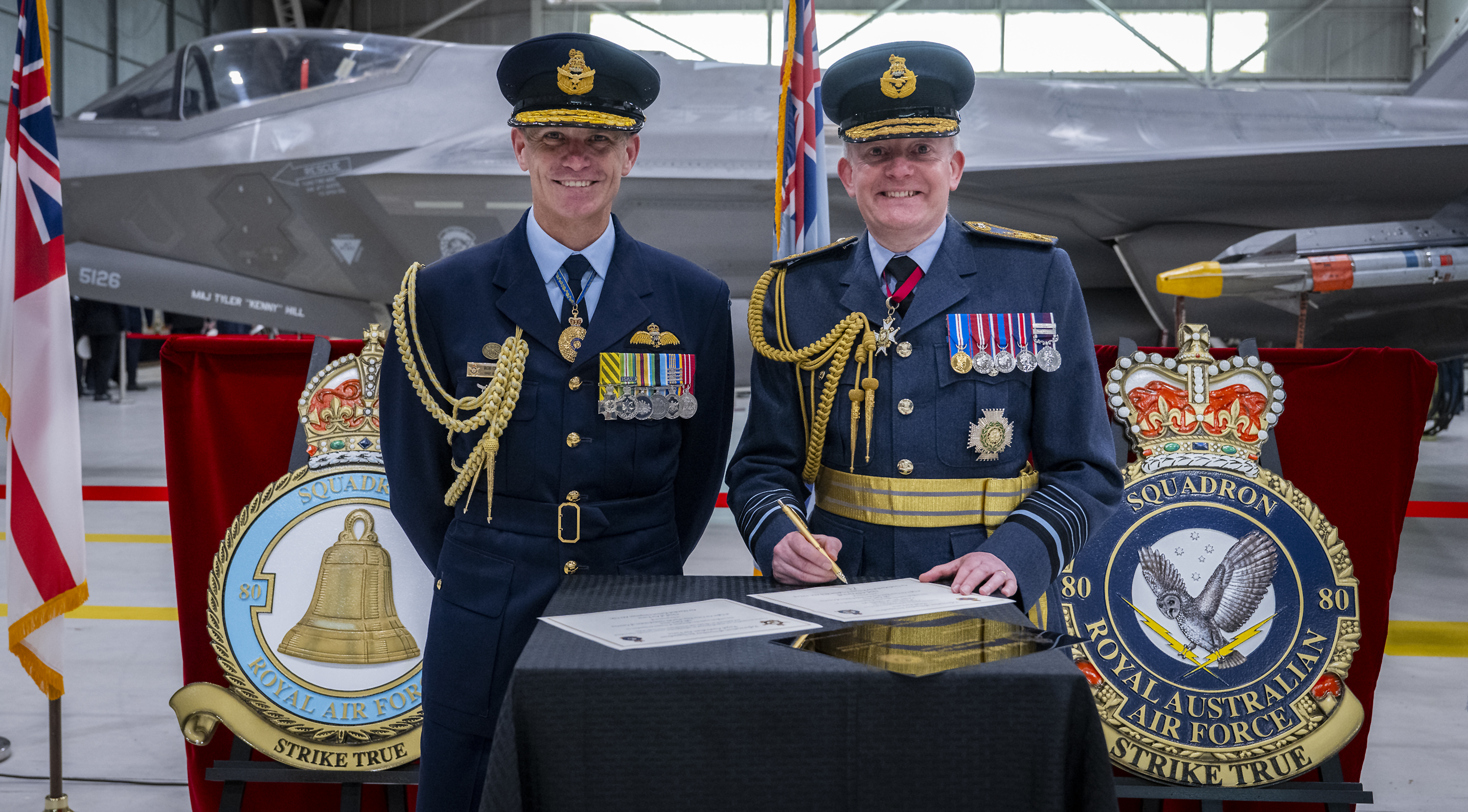 Chief of the Air Staff and Chief of the Air Force signing documents and smiling.