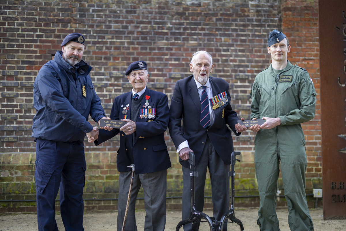 Two veterans standing holding their plaques with two serving Armed Forces personnel.