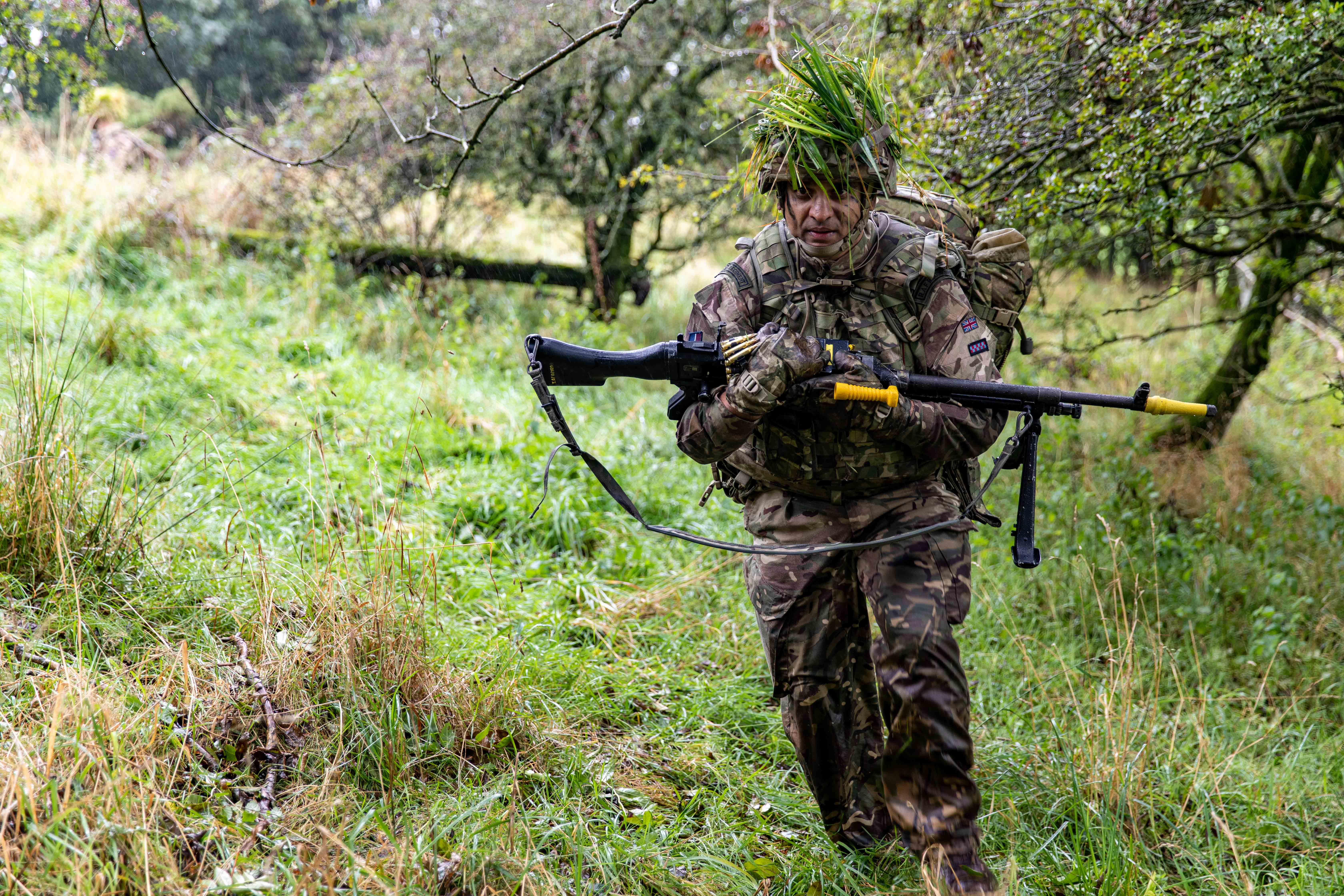 Soldier carrying rifle through countryside