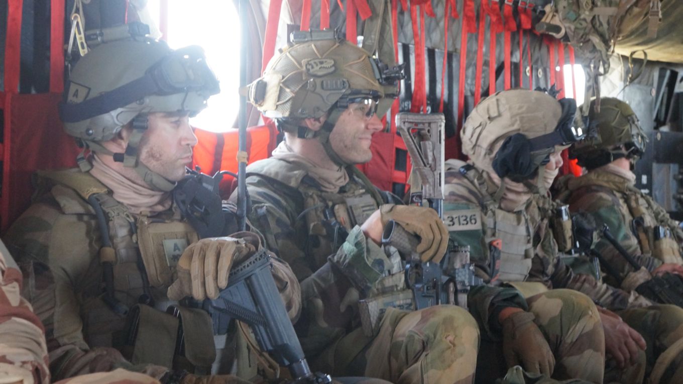 Four personnel in full gear and rifles. 