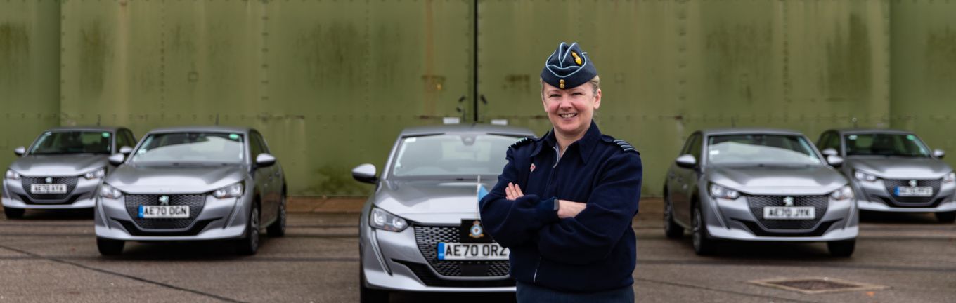 Image shows Station Commander, Group Captain Jo Lincoln standing in front of the five new Peugeot e-208 electric vehicles at RAF Wittering.