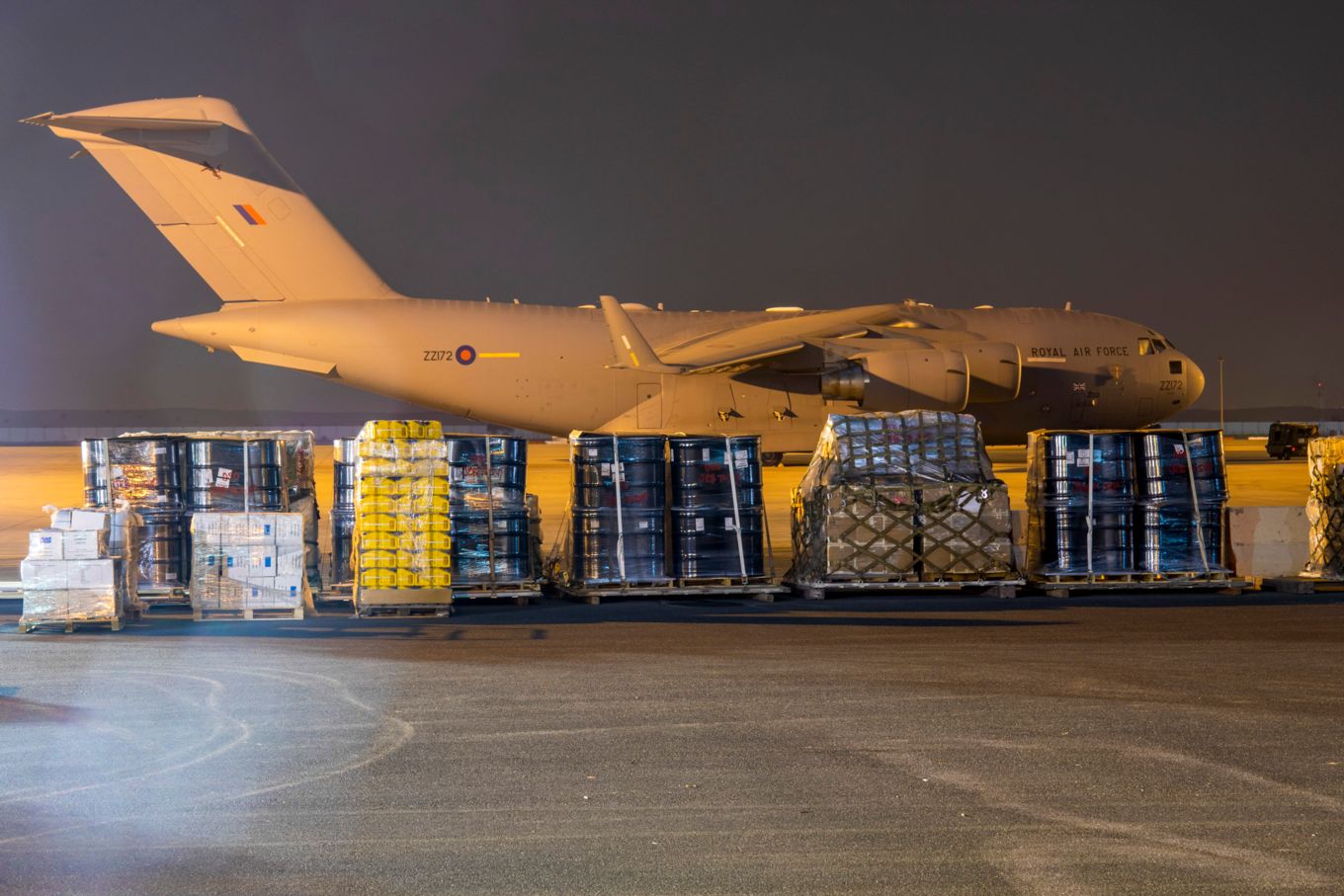 Image shows an RAF C-17 aircraft at night behind aid that has just been unloaded from it.