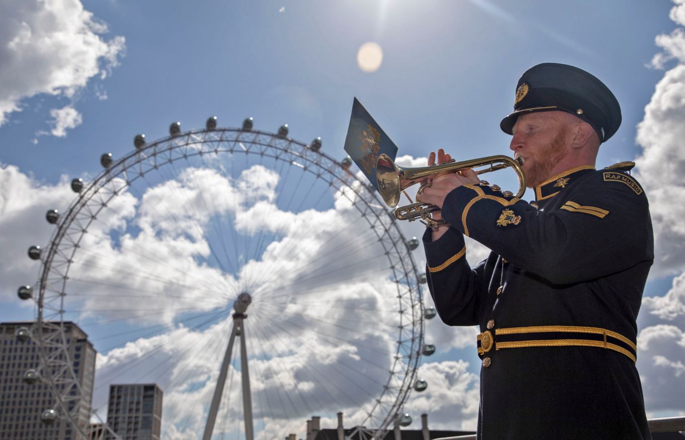 A Trumpeter plays the last post in-front of the London Eye. 