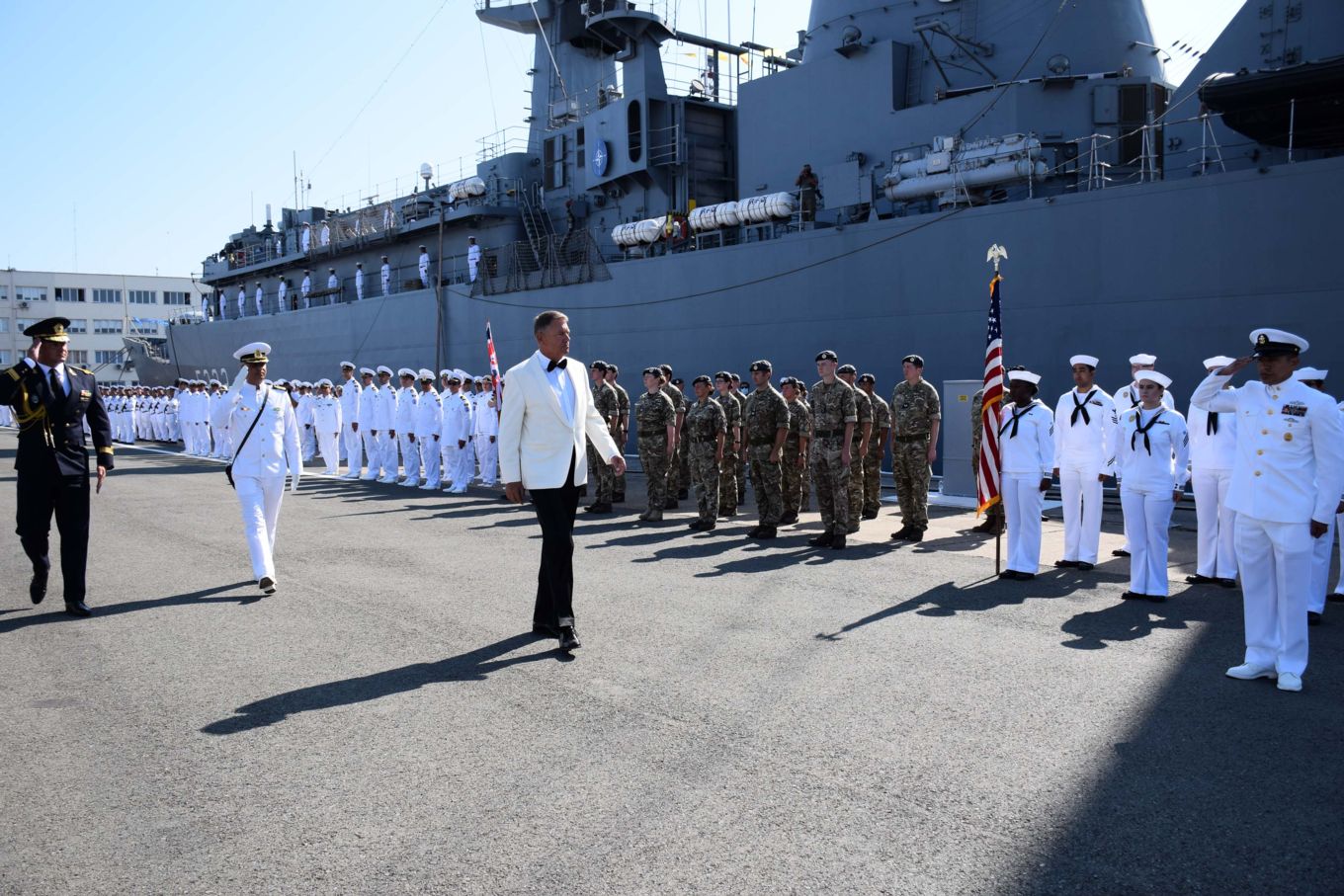 Navy and RAF personnel stand in parade, with President of Romania, Klaus Johannis leading the address.