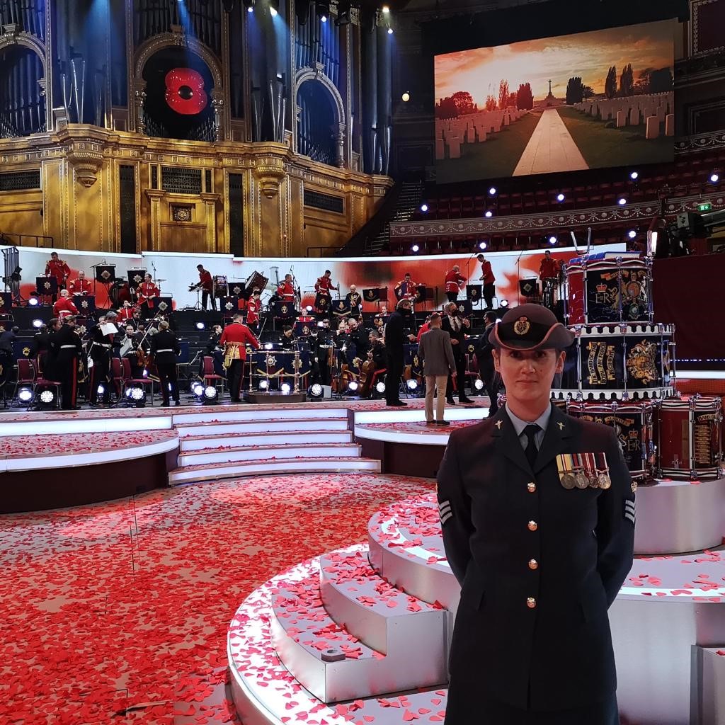Flight Sergeant Chambers stands in-front of an RAF band and stage filled with red heart confetti.