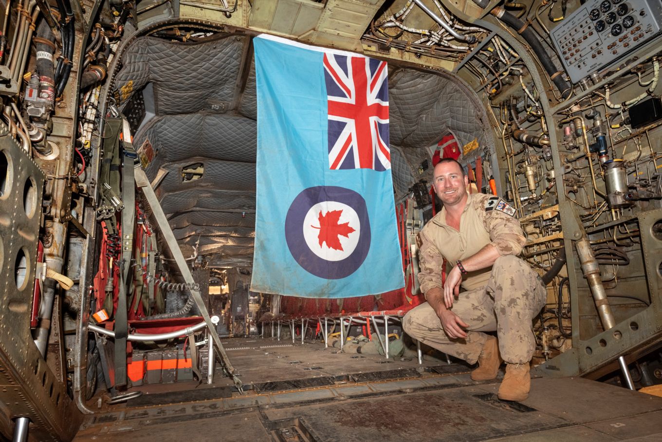 Image shows Captain Stewart in the back of Chinook helicopter with the Royal Canadian Air Force ensign.