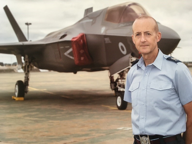 Warrant Officer Graham Spark standing in-front of a F35 Lightning aircraft.. 
