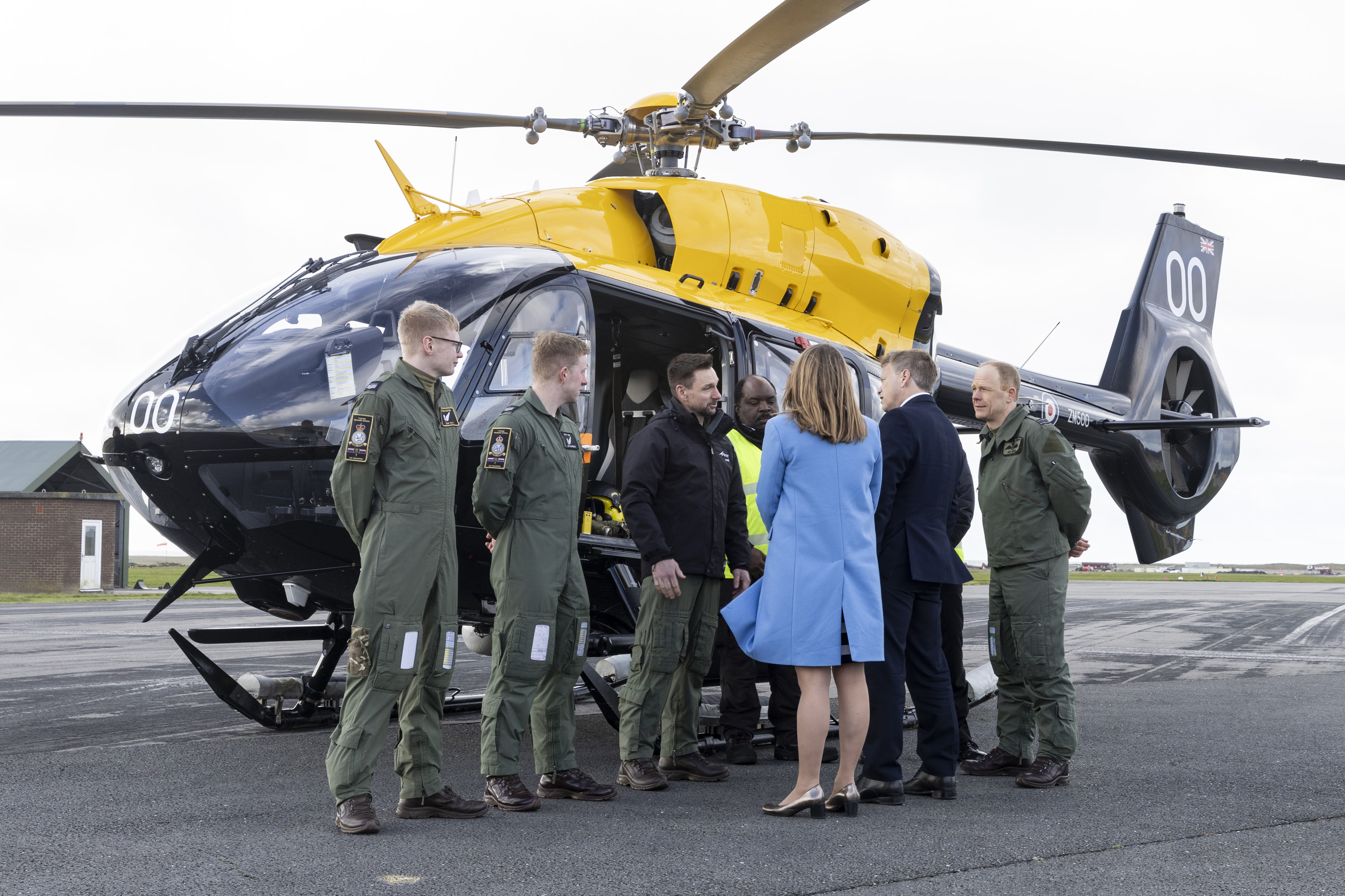 Defence Secretary Grant Shapps chats to group of personnel next to a helicopter on the runway