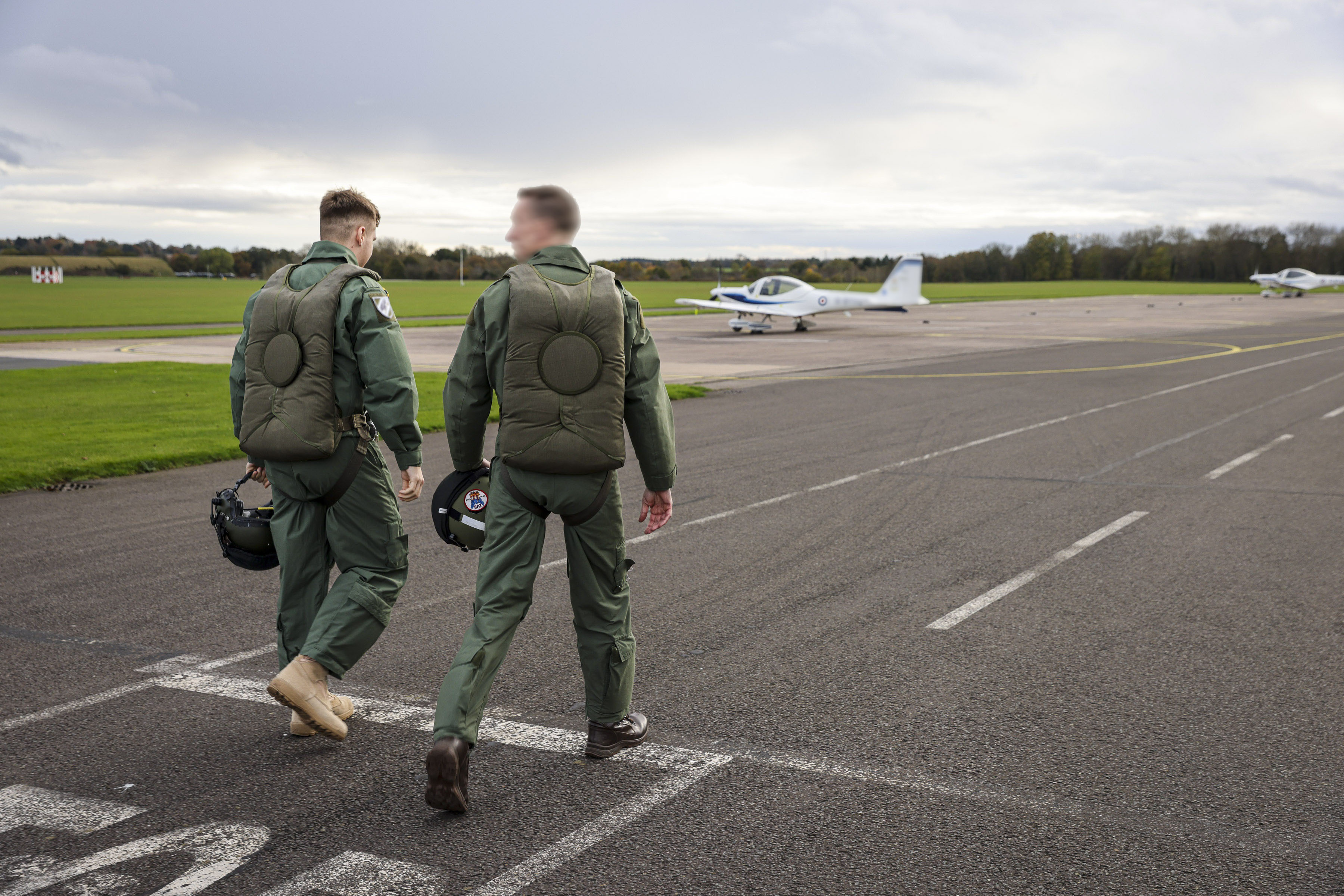 Two pilots walking together away from the camera on the runway