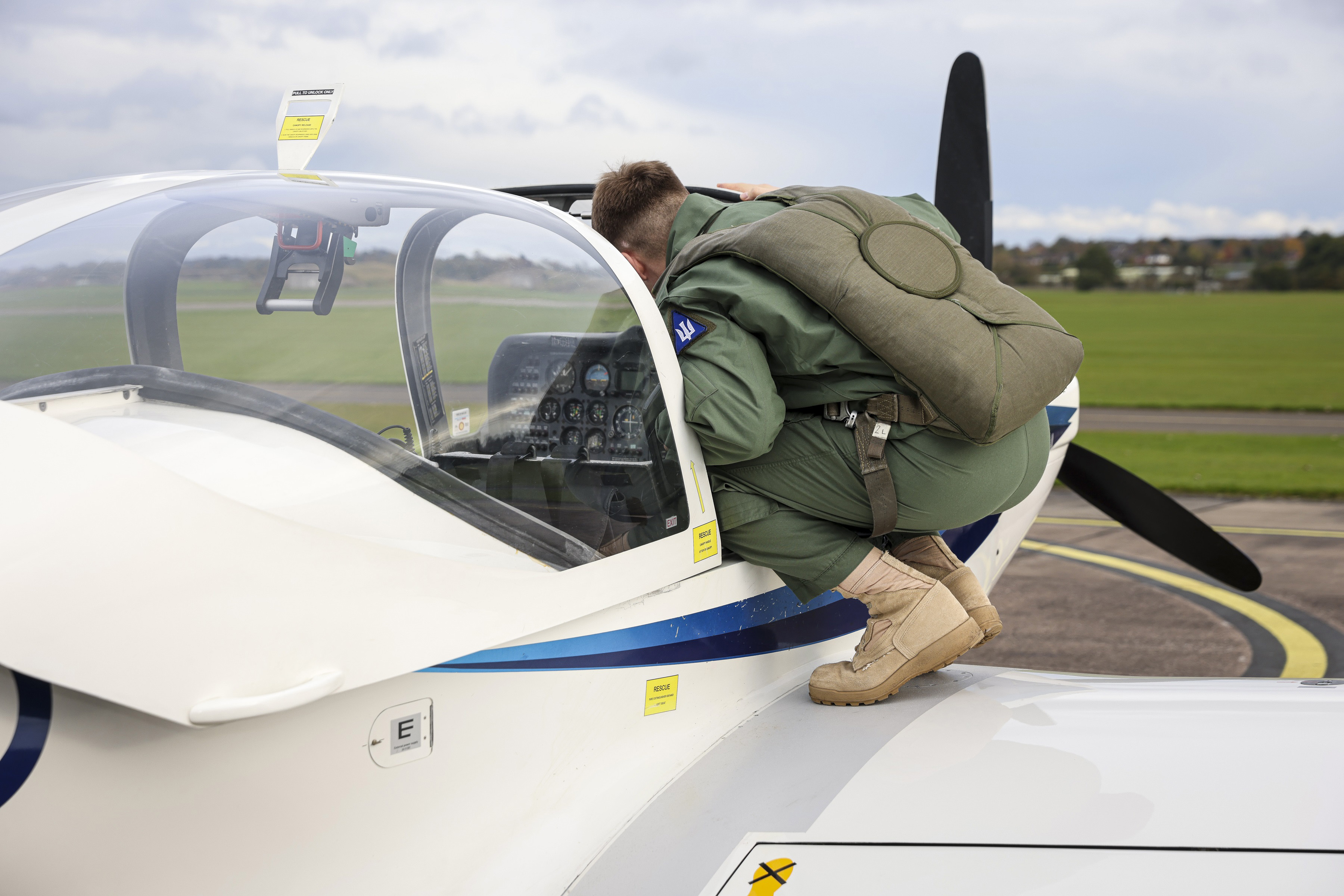 Pilot standing on tutor wing looking into the aircraft's cockpit