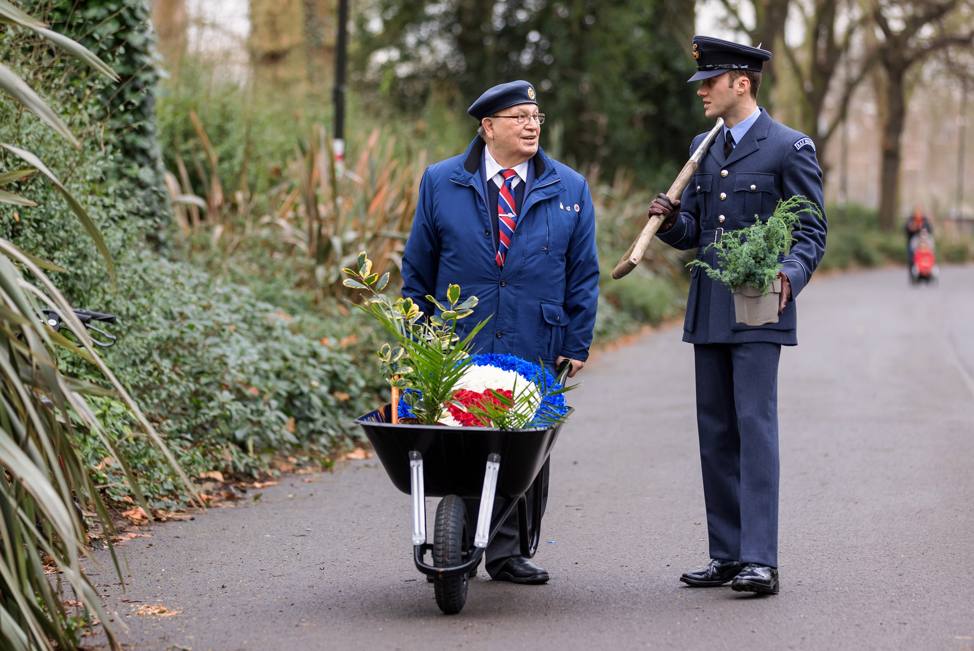 Veteran and Personnel talk with wheelbarrow, spade, and plants.