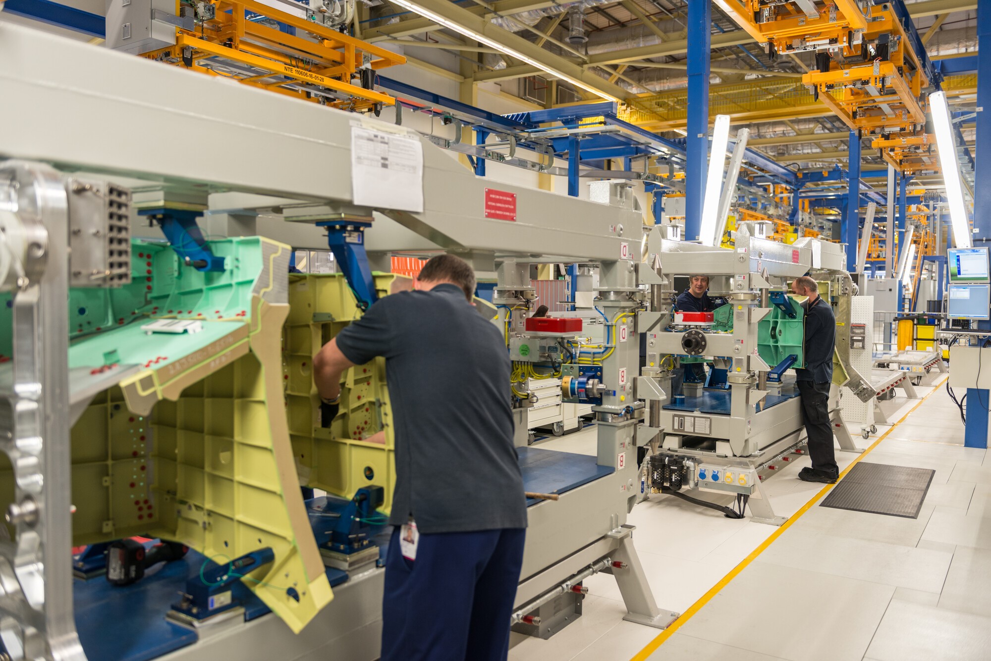 Image shows engineers working with aircraft parts in factory. 