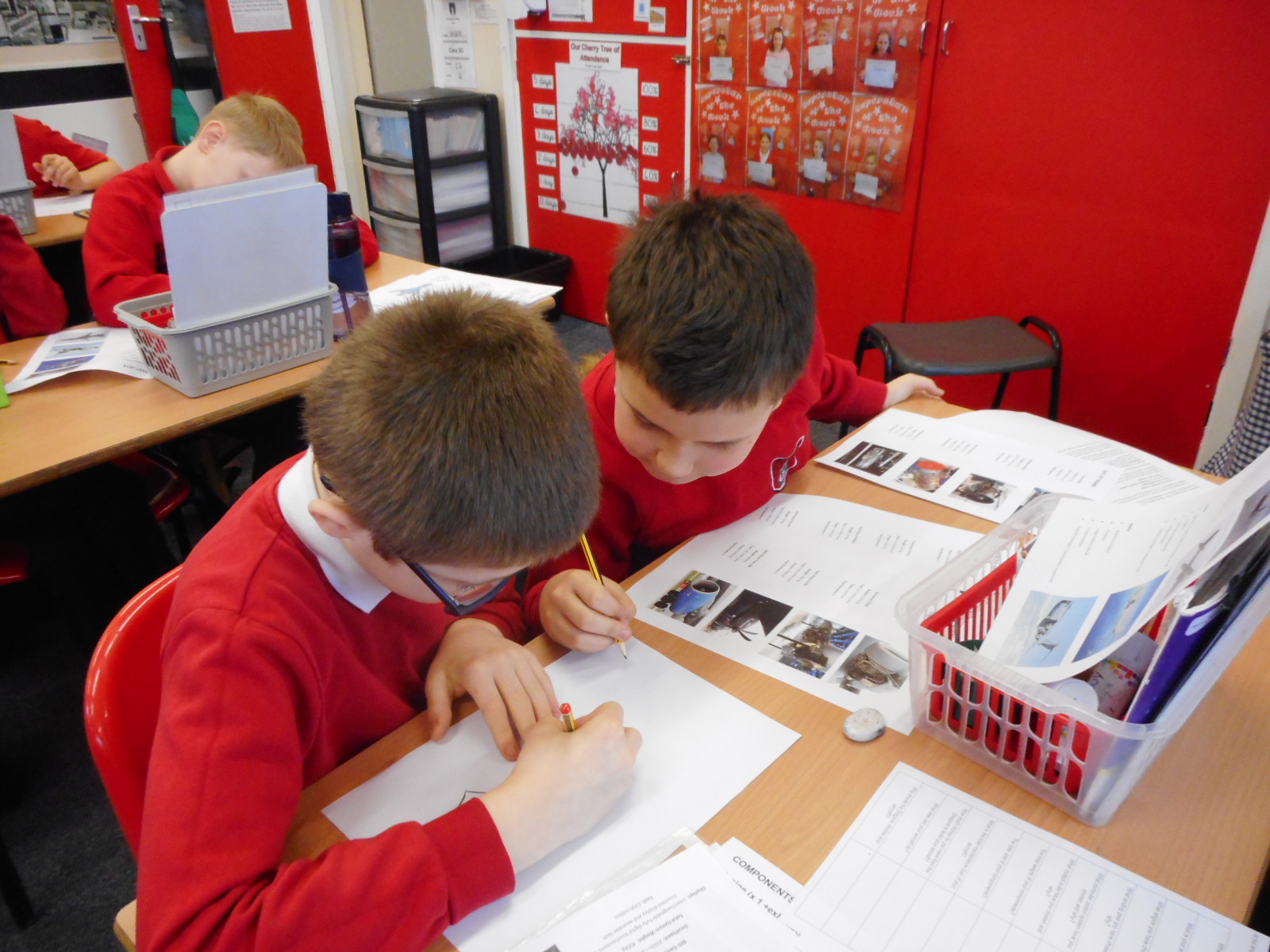Children sit at table working on their drawing design.