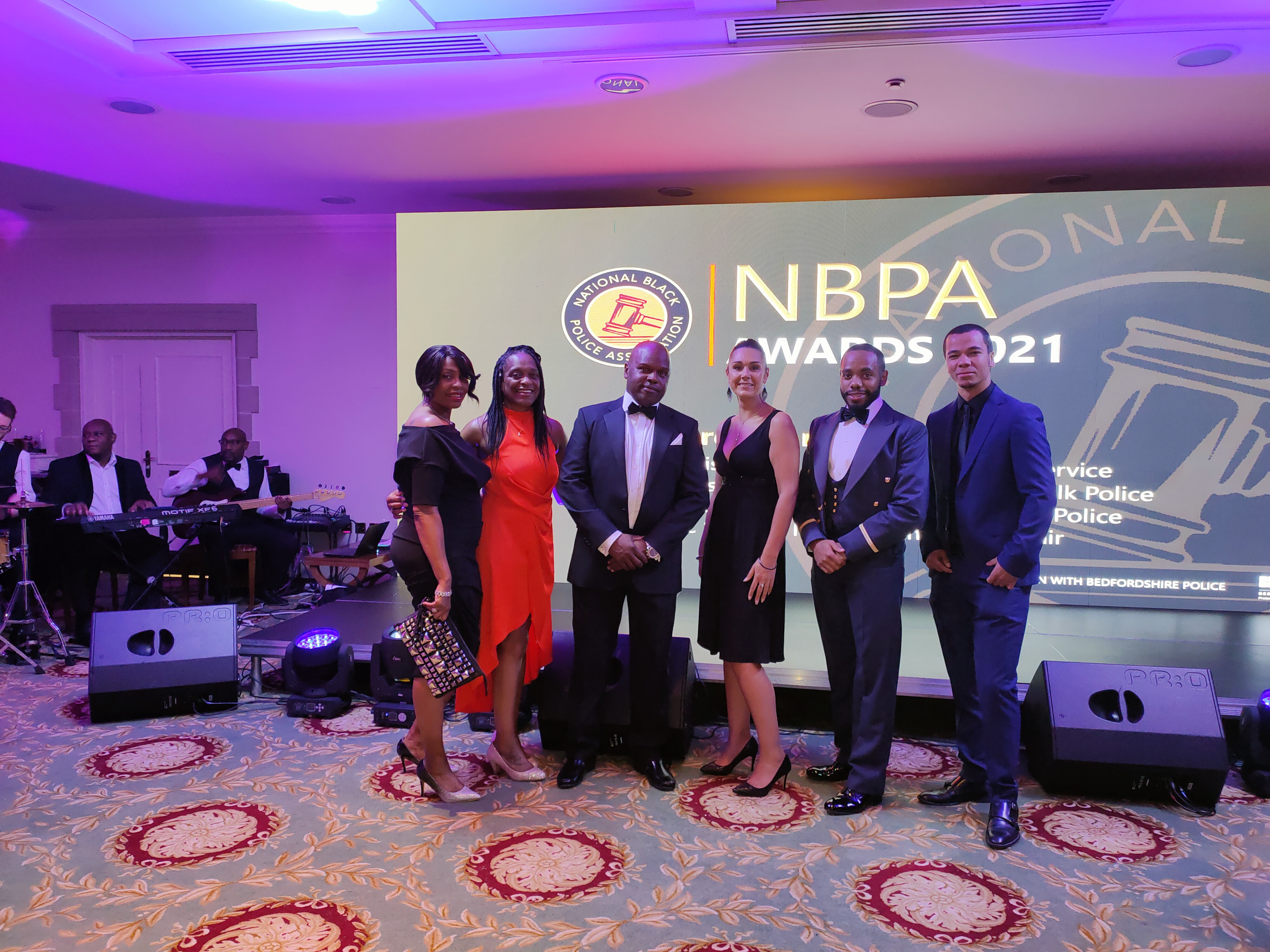 Personal and notable figures stand in front of presentation board.