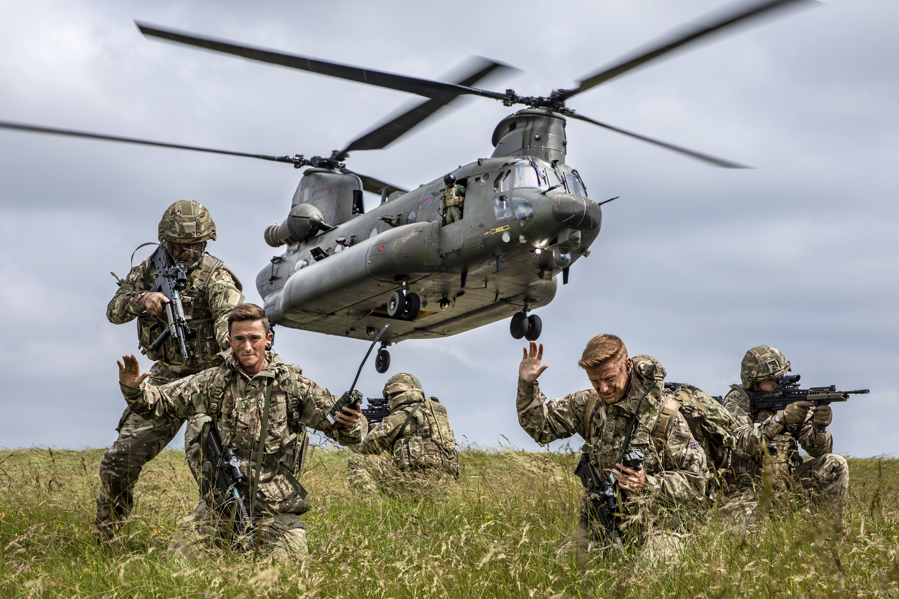 Regiment on the ground with Chinook helicopter in the background.