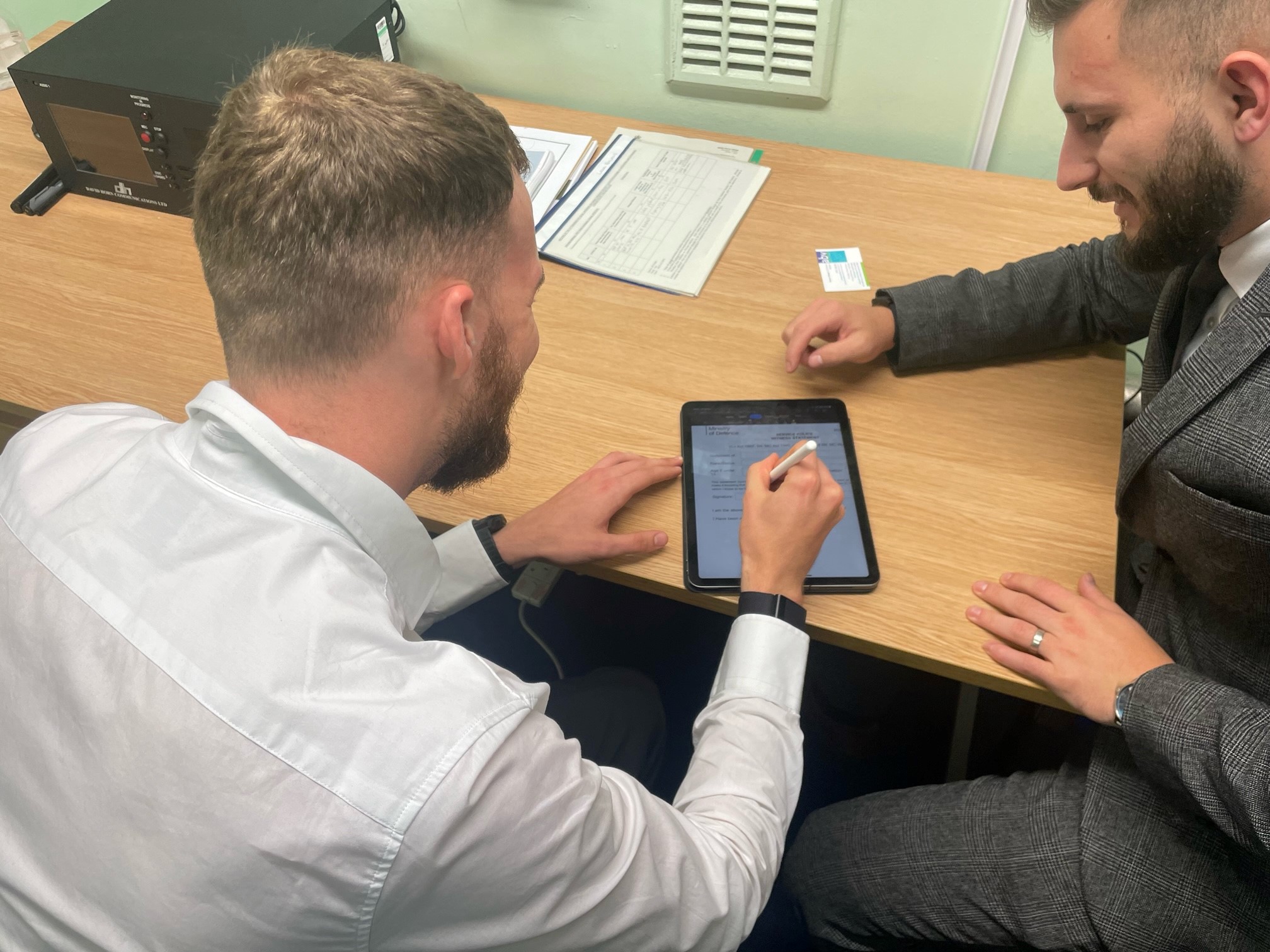 Image shows two looking at a tablet device on the table.