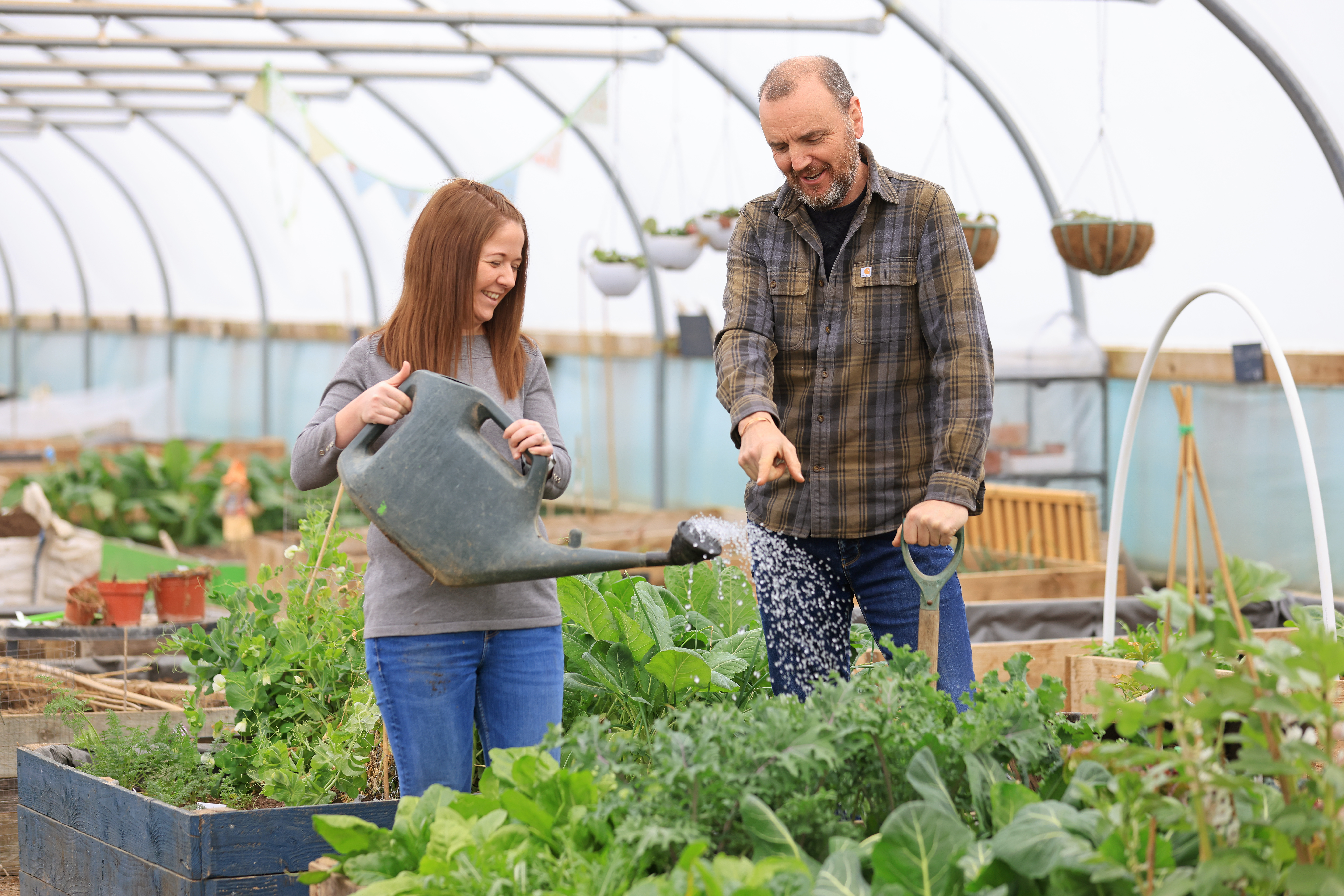 Amileigh holds a watering can over a plant box with John.