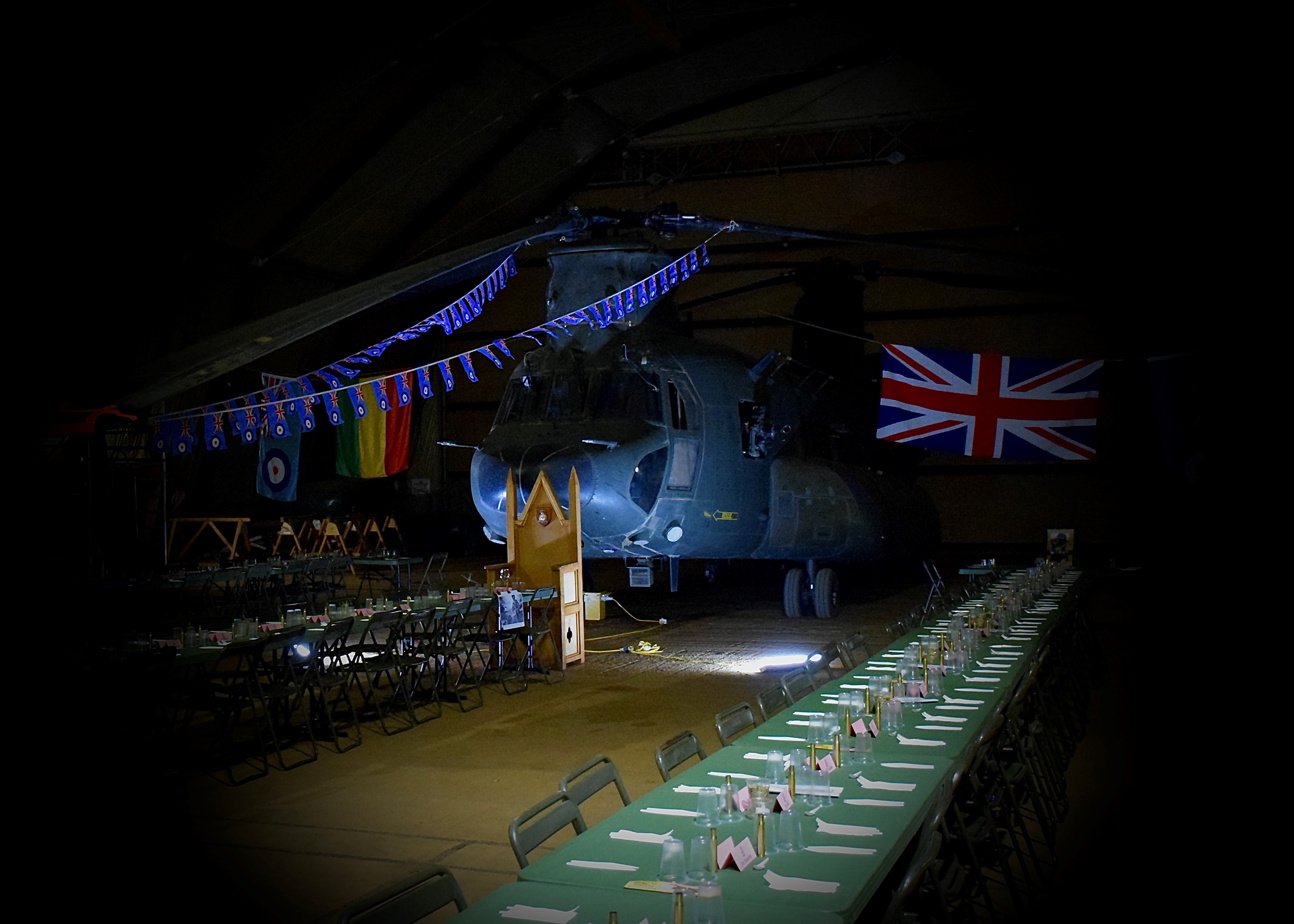 Chinook and flags backdrop behind rows of tables set for eating.