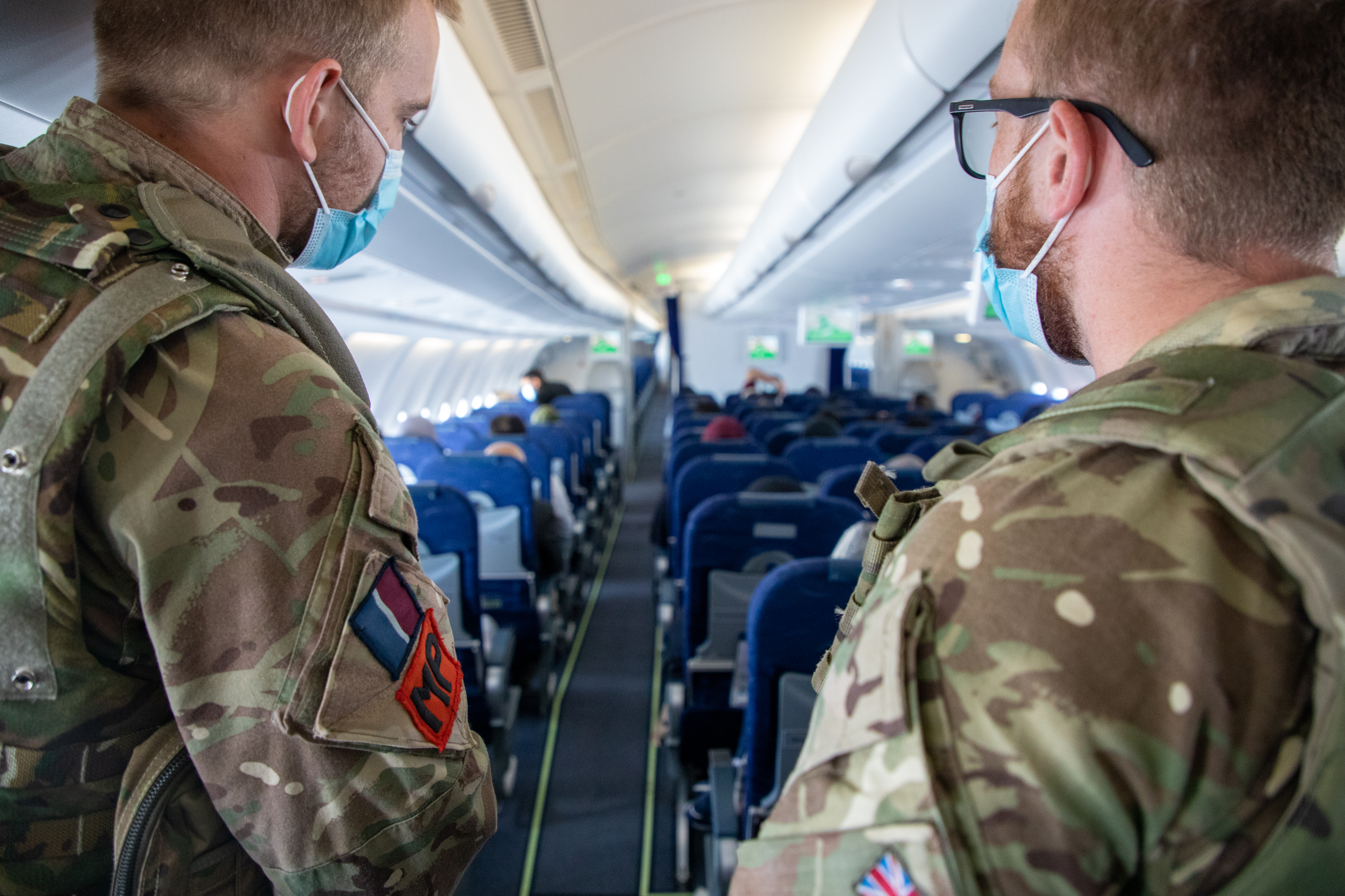 RAF Police look over passengers inside aircraft.