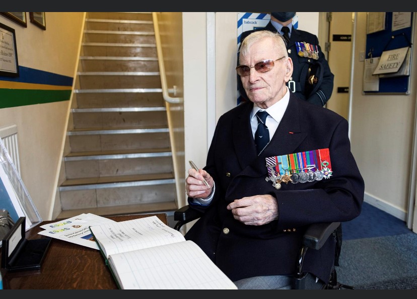 Image shows wheelchair using veteran signing a book.