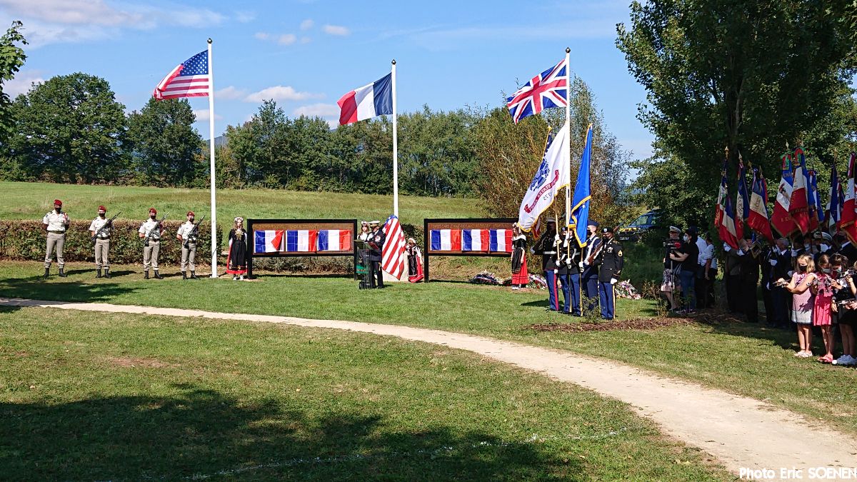 Flags flying by the memorial with Personnel and audience.