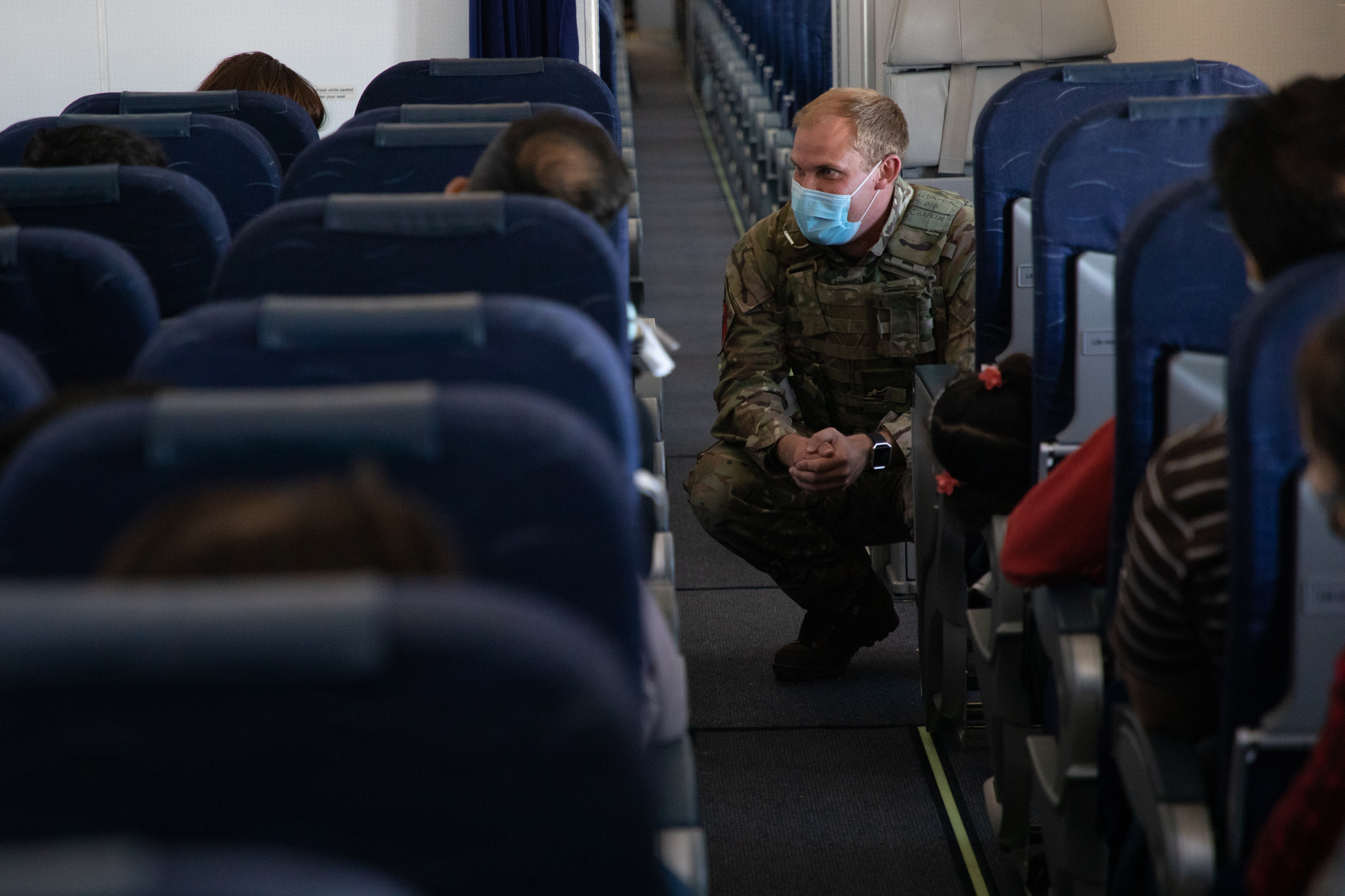 RAF Police crouched down talking to passengers inside aircraft.