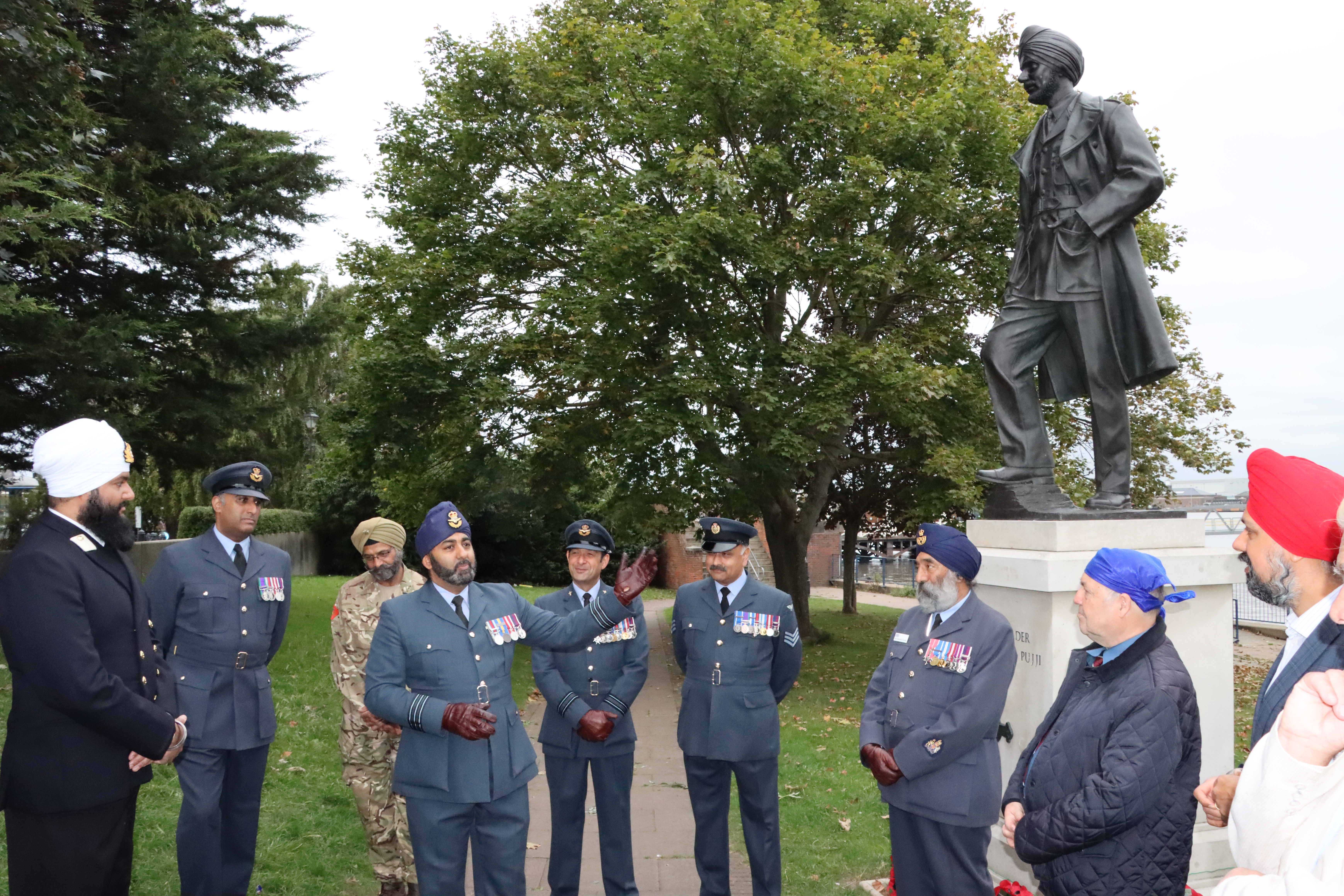 Personnel in Sikh attire stand by the statue.