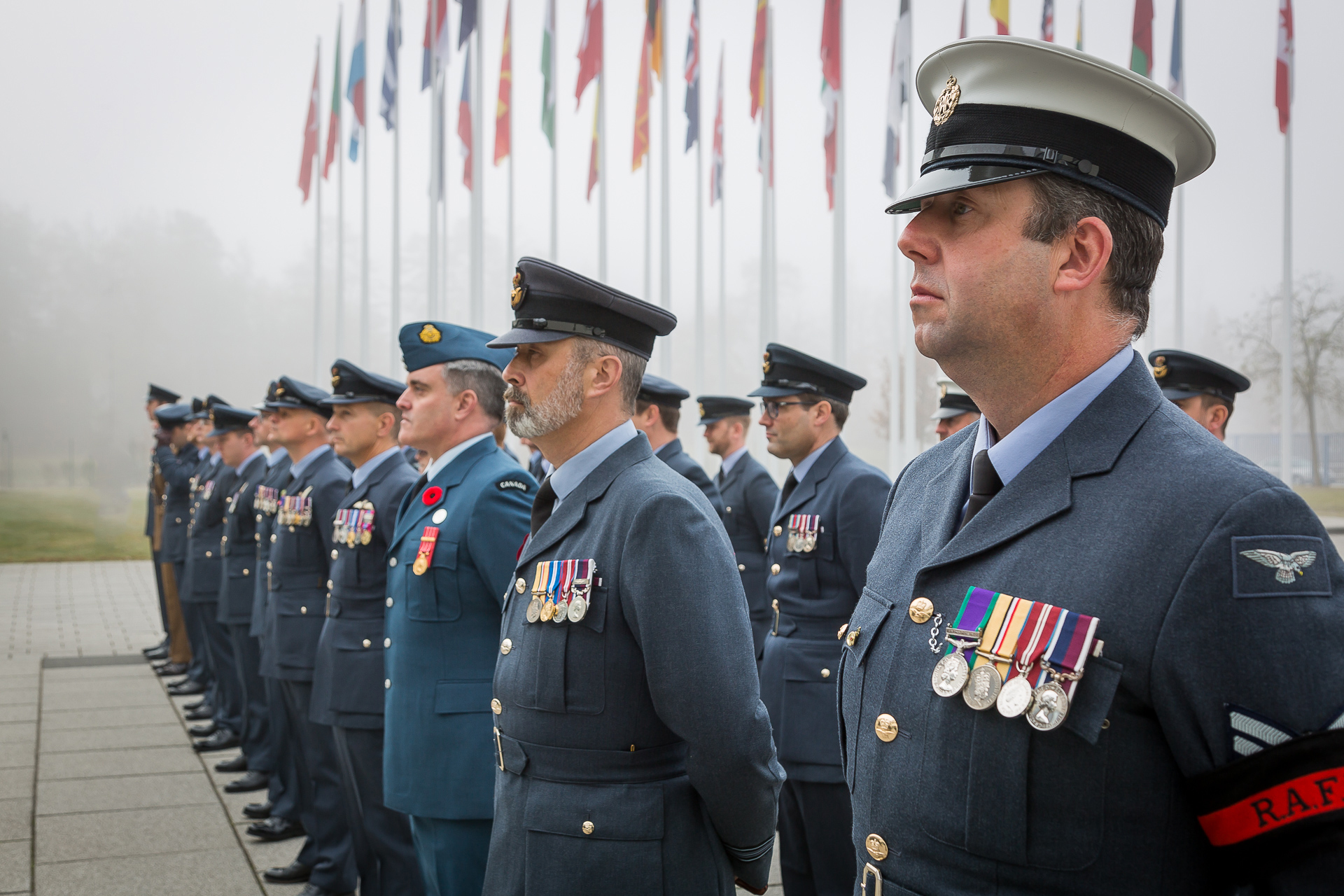 Personnel stand during parade, with flag posts in background.