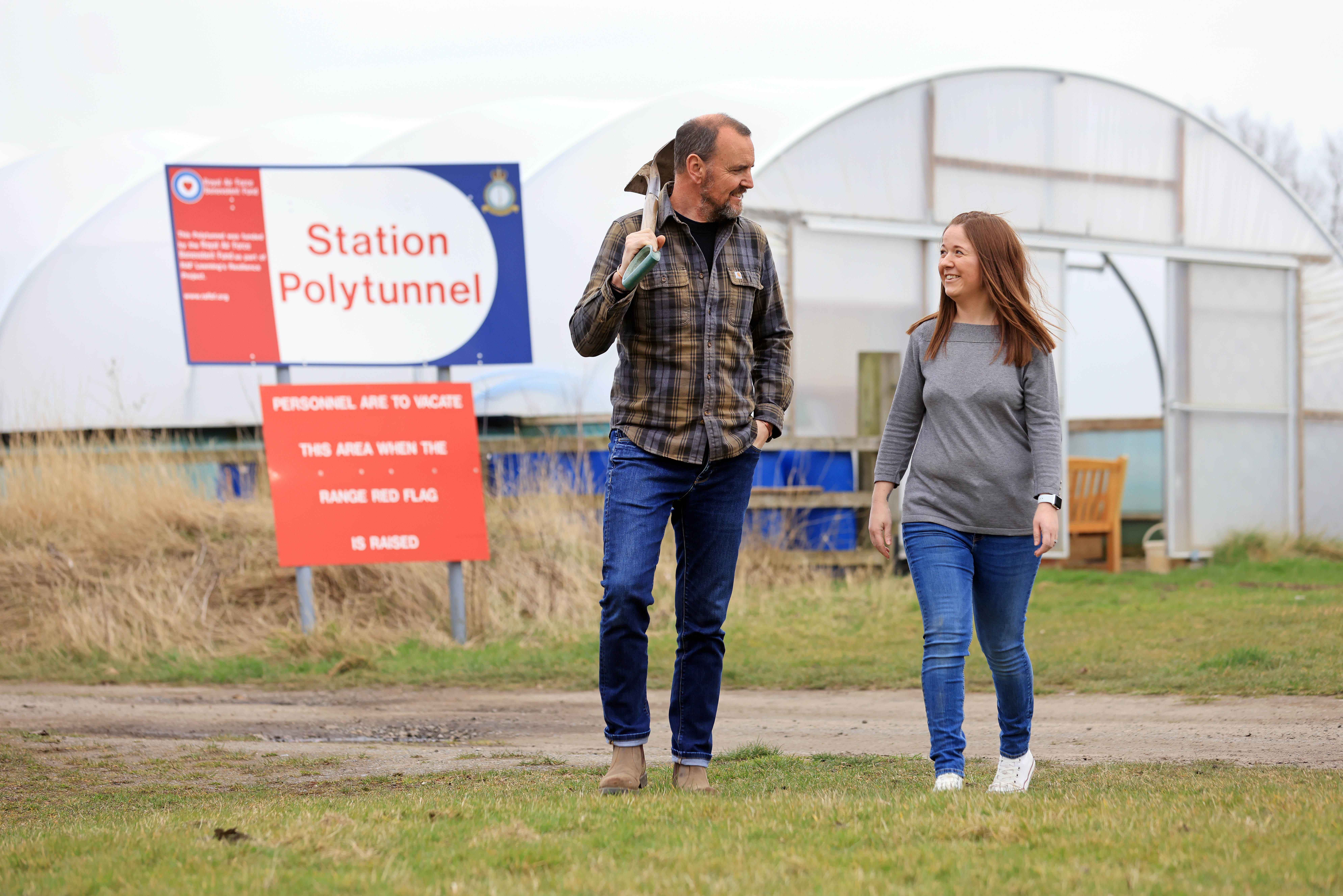 John carries a shovel as he and Amileigh walk away from Polytunnel greenhouse.