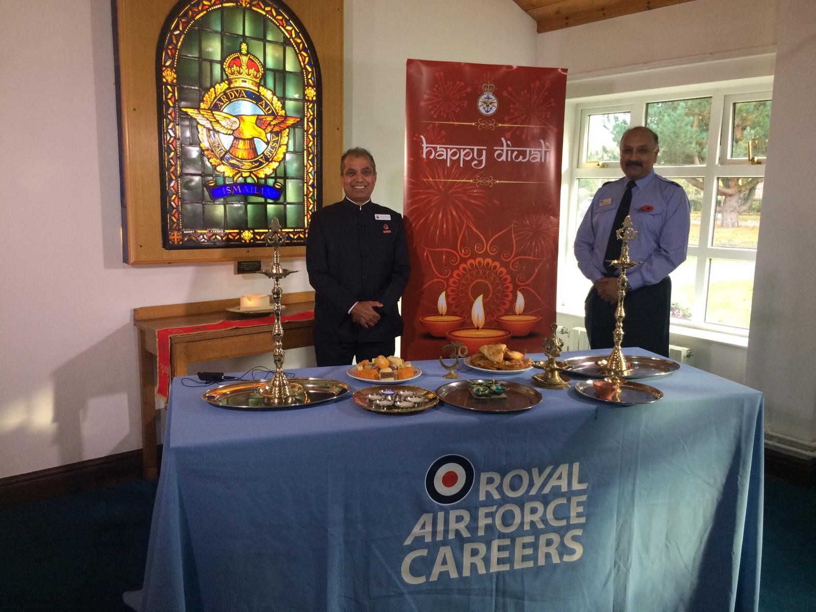 Personnel inside a Hindi temple, by table with food and candles.