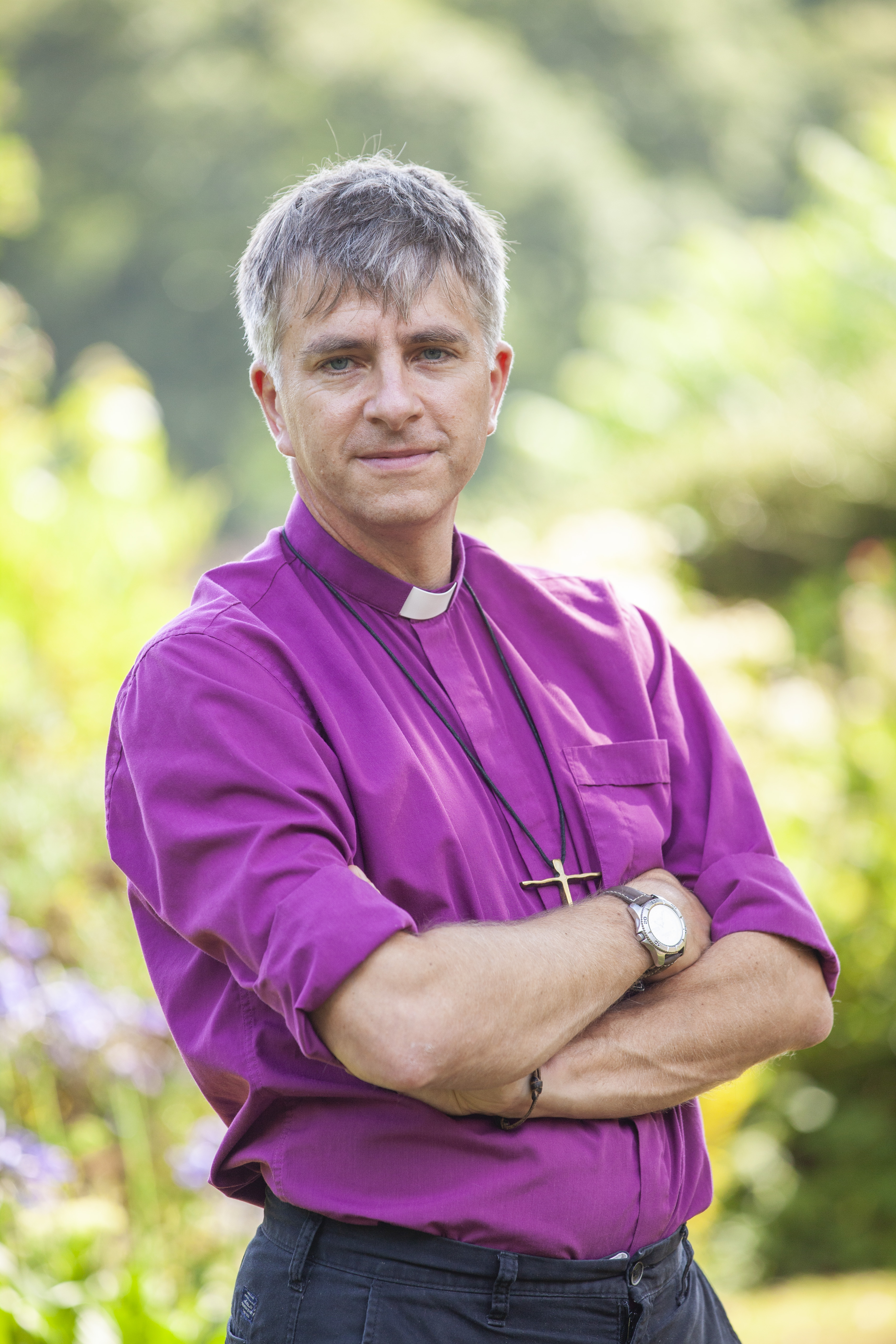 Bishop Hugh Nelson stands cross armed.