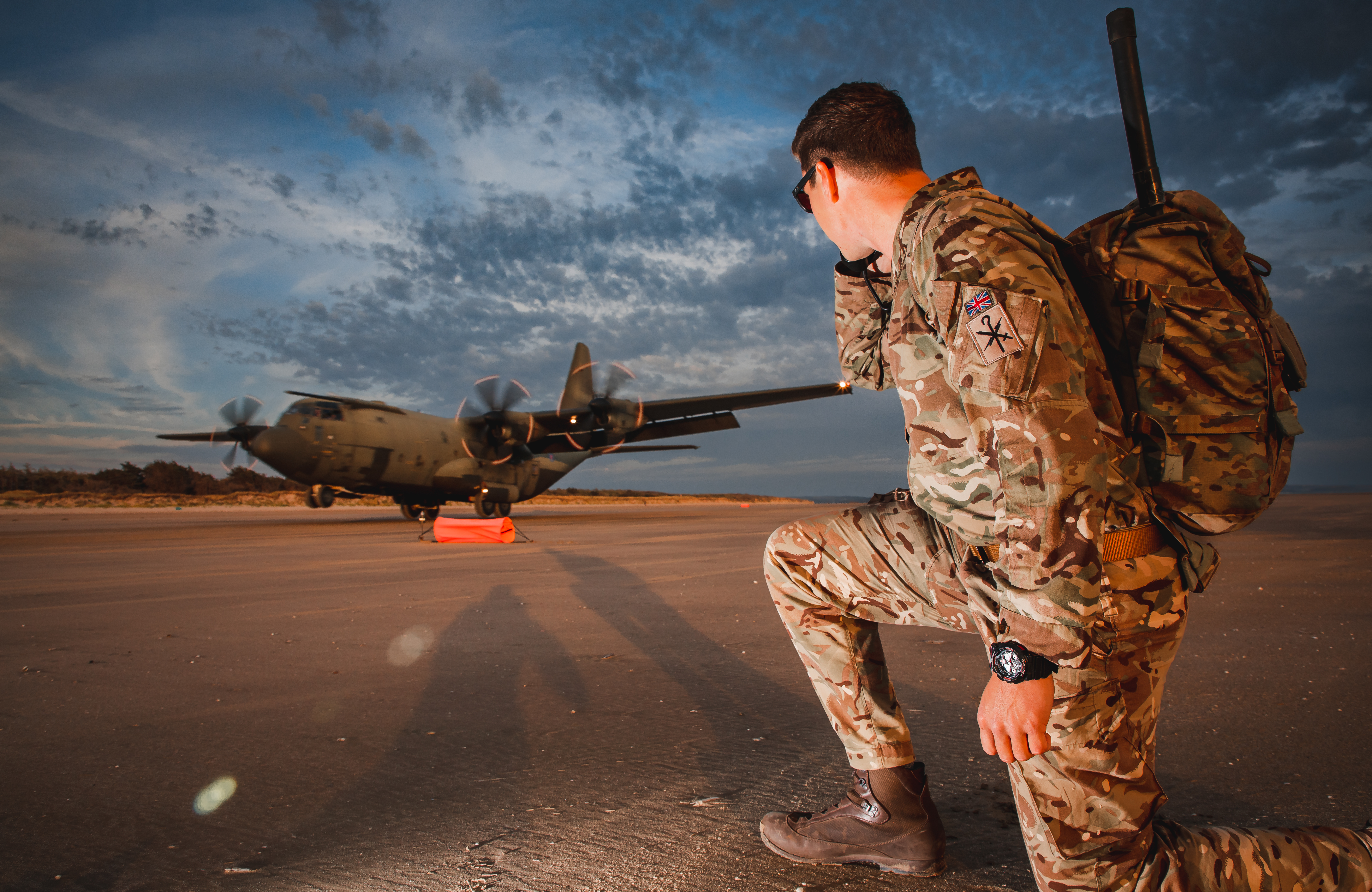 Image shows RAF aviator kneeling, as the Hercules aircraft takes off.