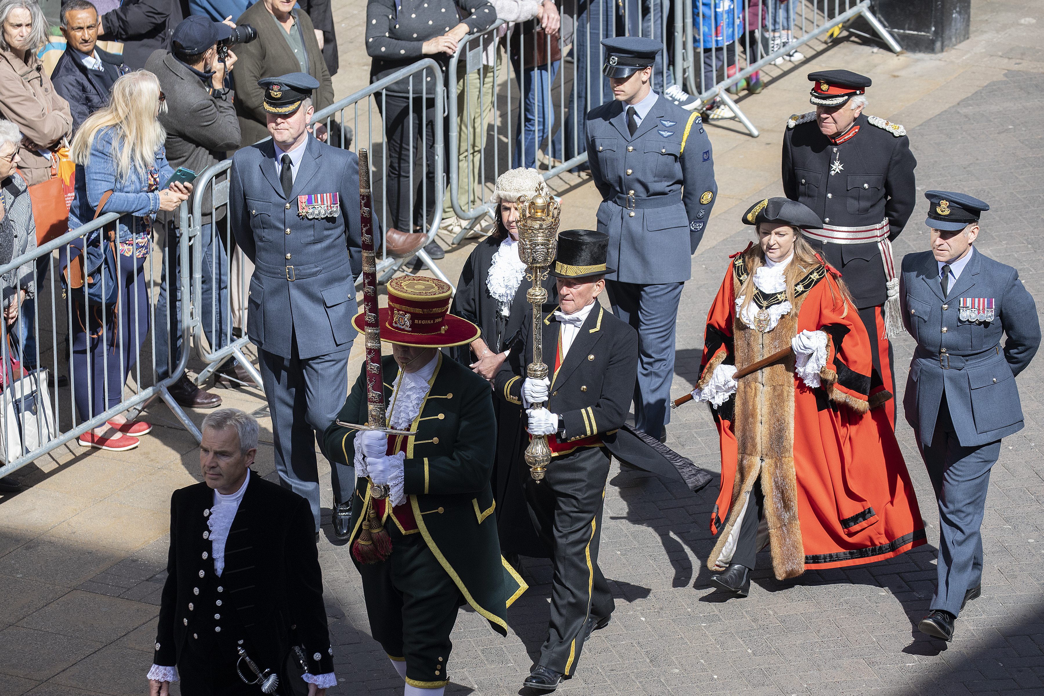 Personnel during parade, with public behind barriers.