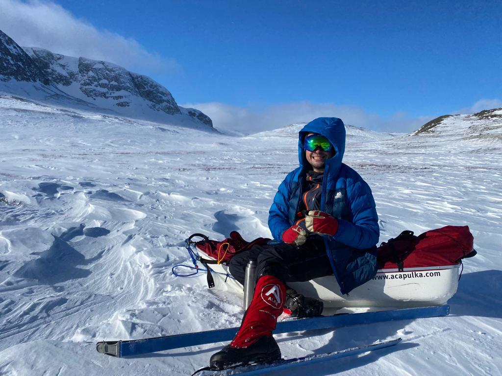 Personnel sits wearing skis on the snow.