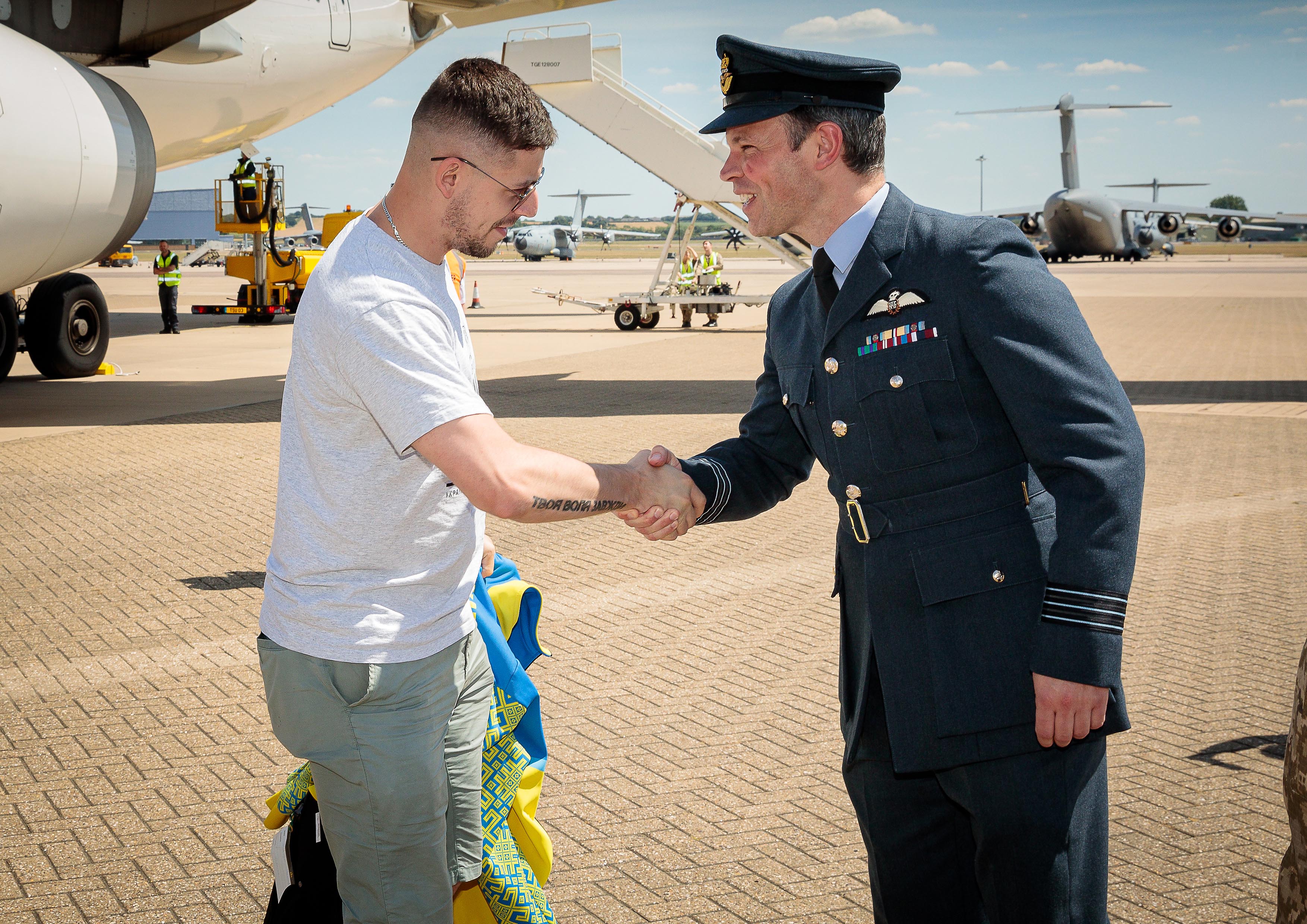 Image shows aviators shaking hands on the airfield.