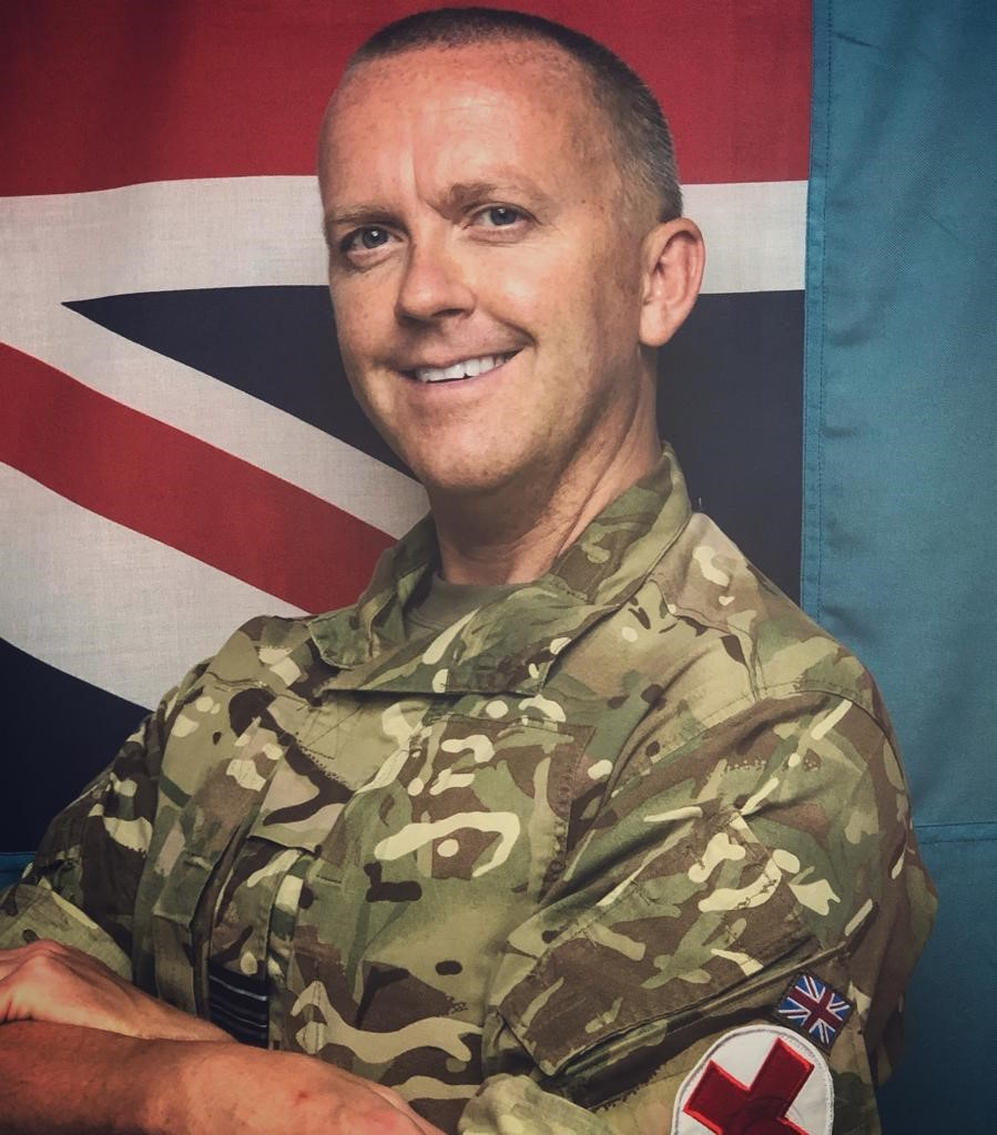 Personnel smiling by Union Jack flag.
